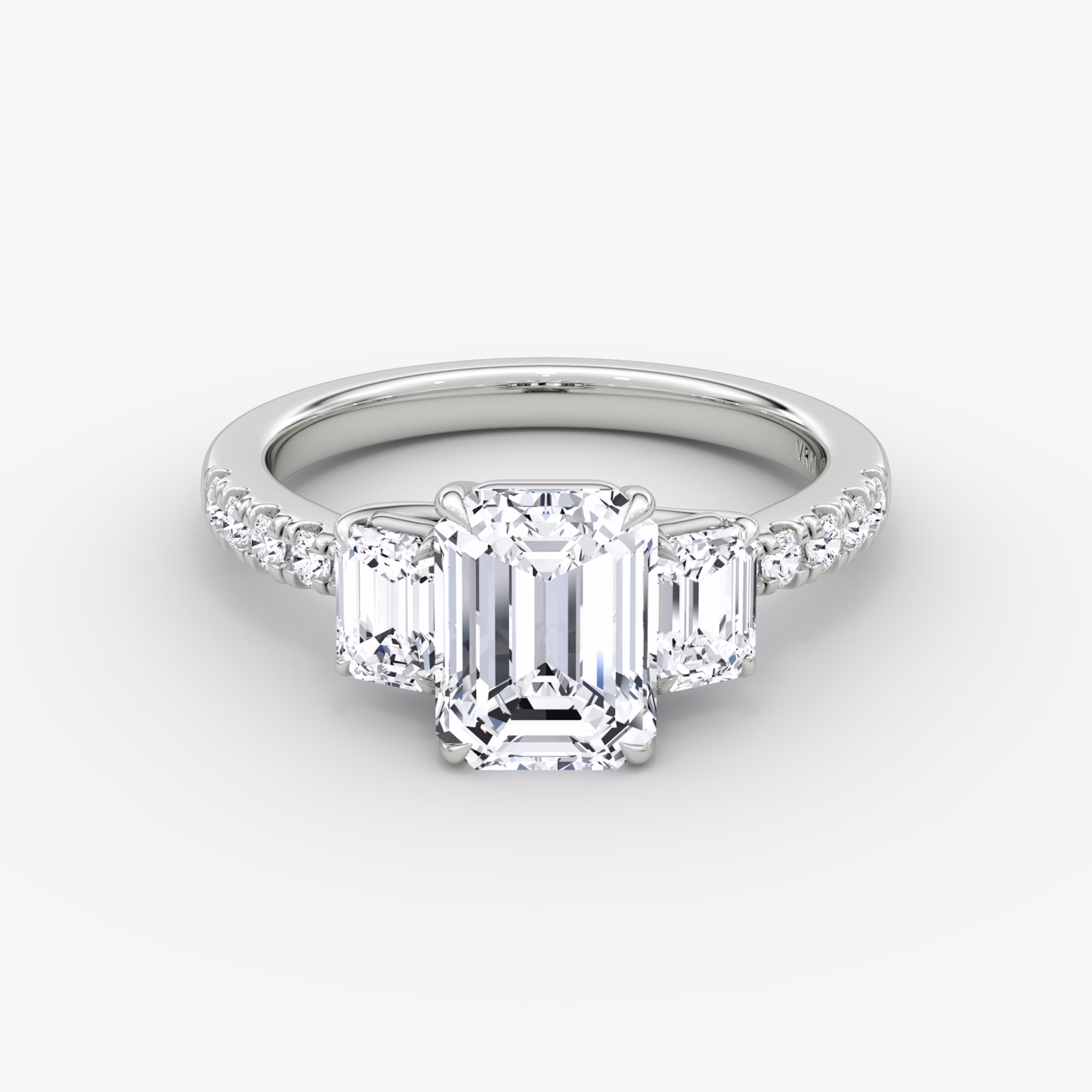 Emerald-cut three-stone diamond ring with pavé band in platinum, VRAI Trellis setting.