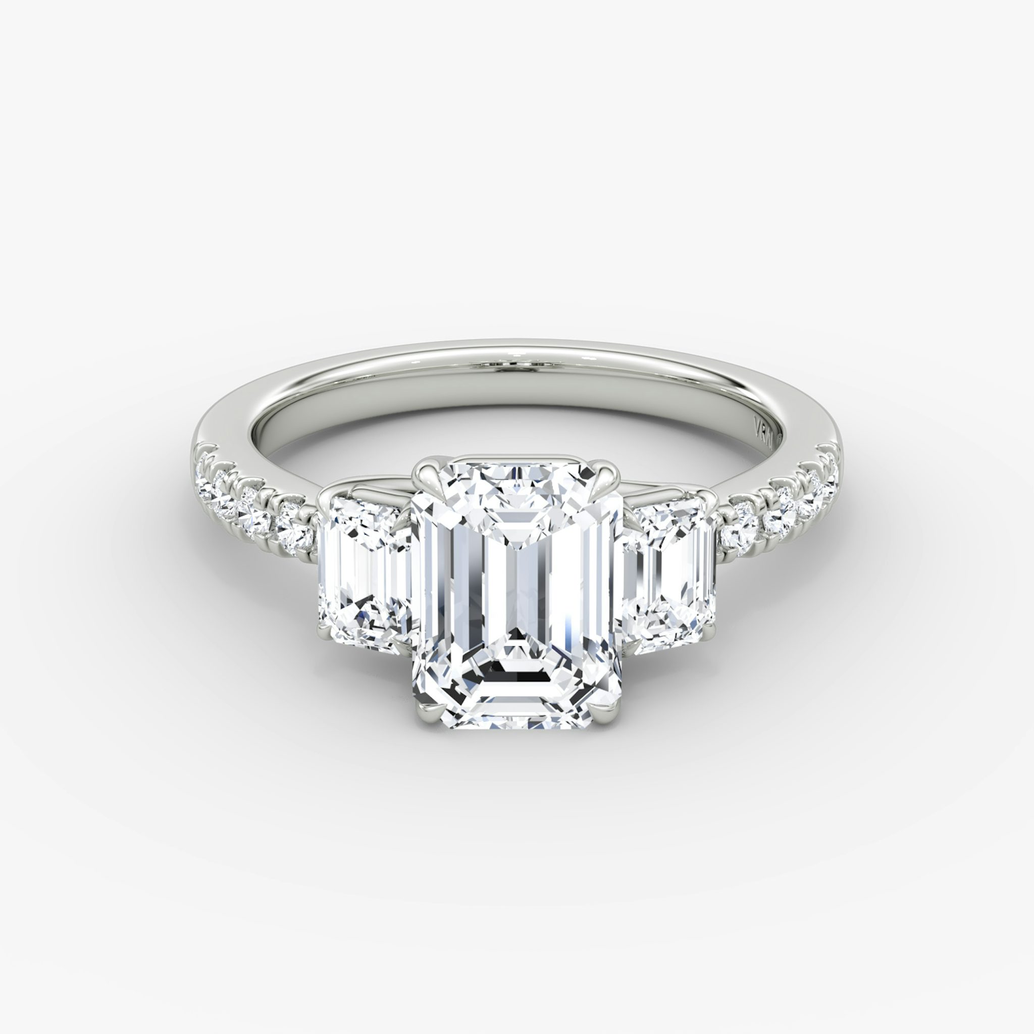Emerald-cut three-stone diamond ring with pavé band in platinum, VRAI Trellis setting.