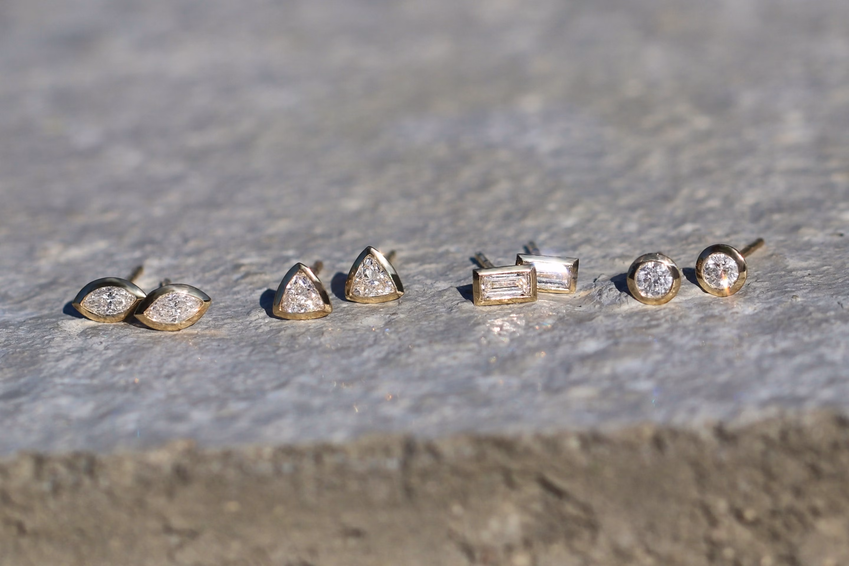 four different types of earrings with lab diamonds of different shapes