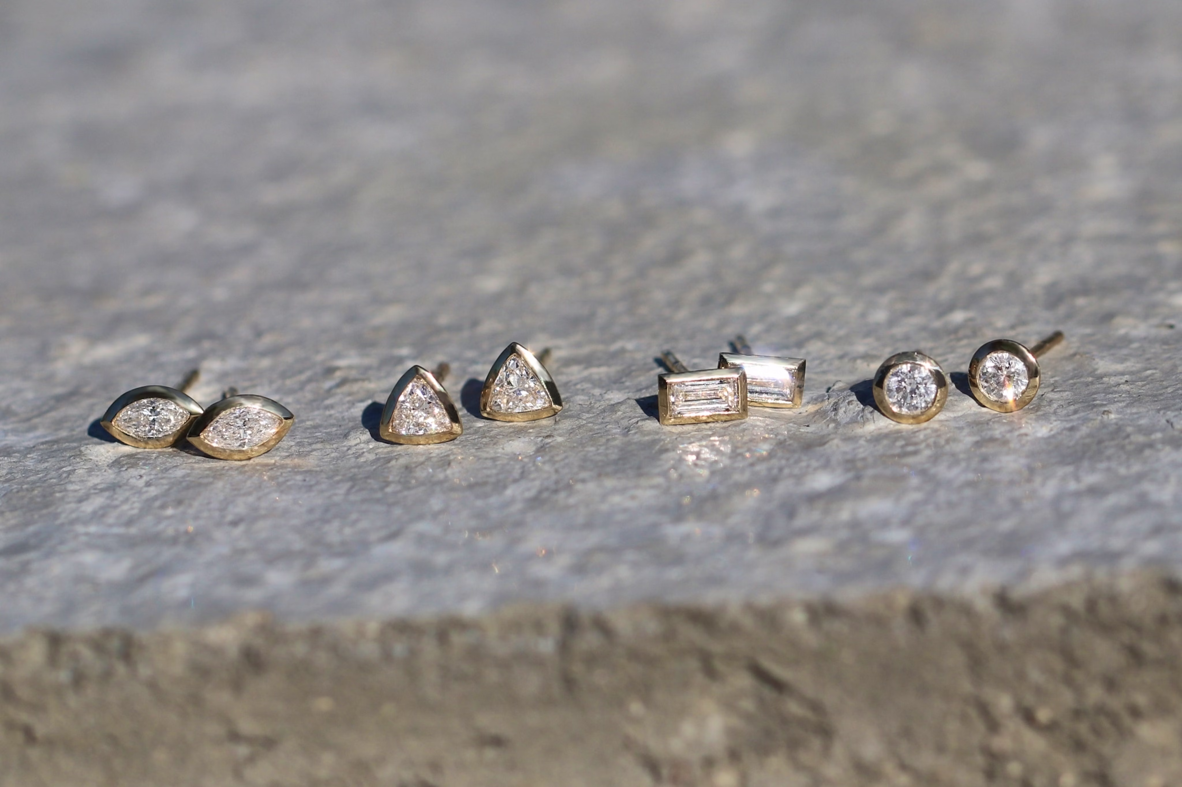four different types of earrings with lab diamonds of different shapes