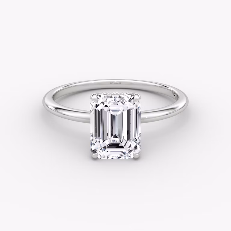Emerald-cut diamond engagement ring with pavé halo on a thin platinum band, VRAI Signature Prong style.