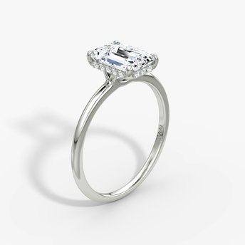 Emerald-cut diamond engagement ring with pavé halo on a thin platinum band, VRAI Signature Prong style.
