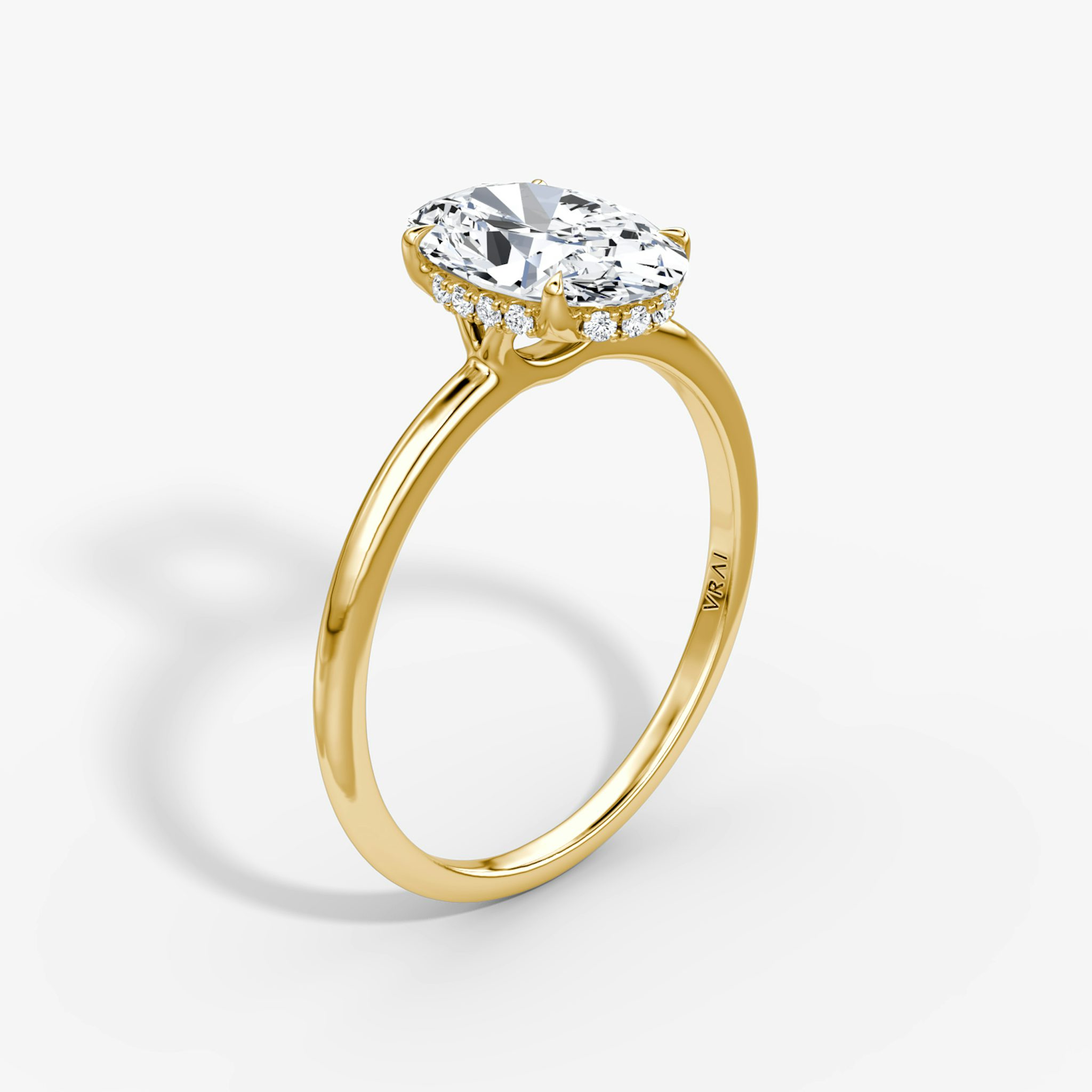 Oval-cut diamond engagement ring in yellow gold with a signature prong setting and hidden halo, designed by VRAI.