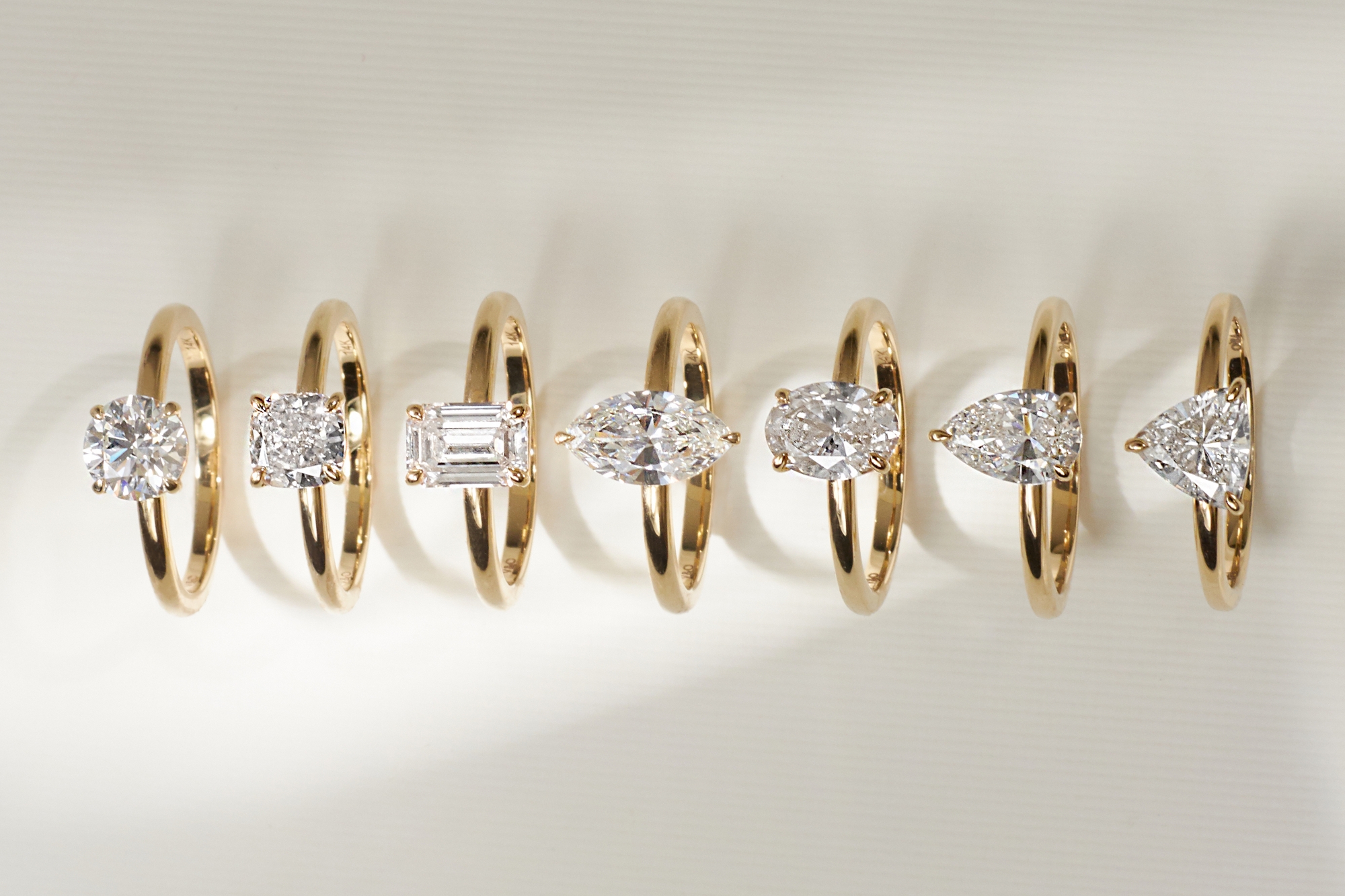 selection of engagement rings with different diamond shapes round brilliant, emerald, princess cut, marquise, pear, trillion