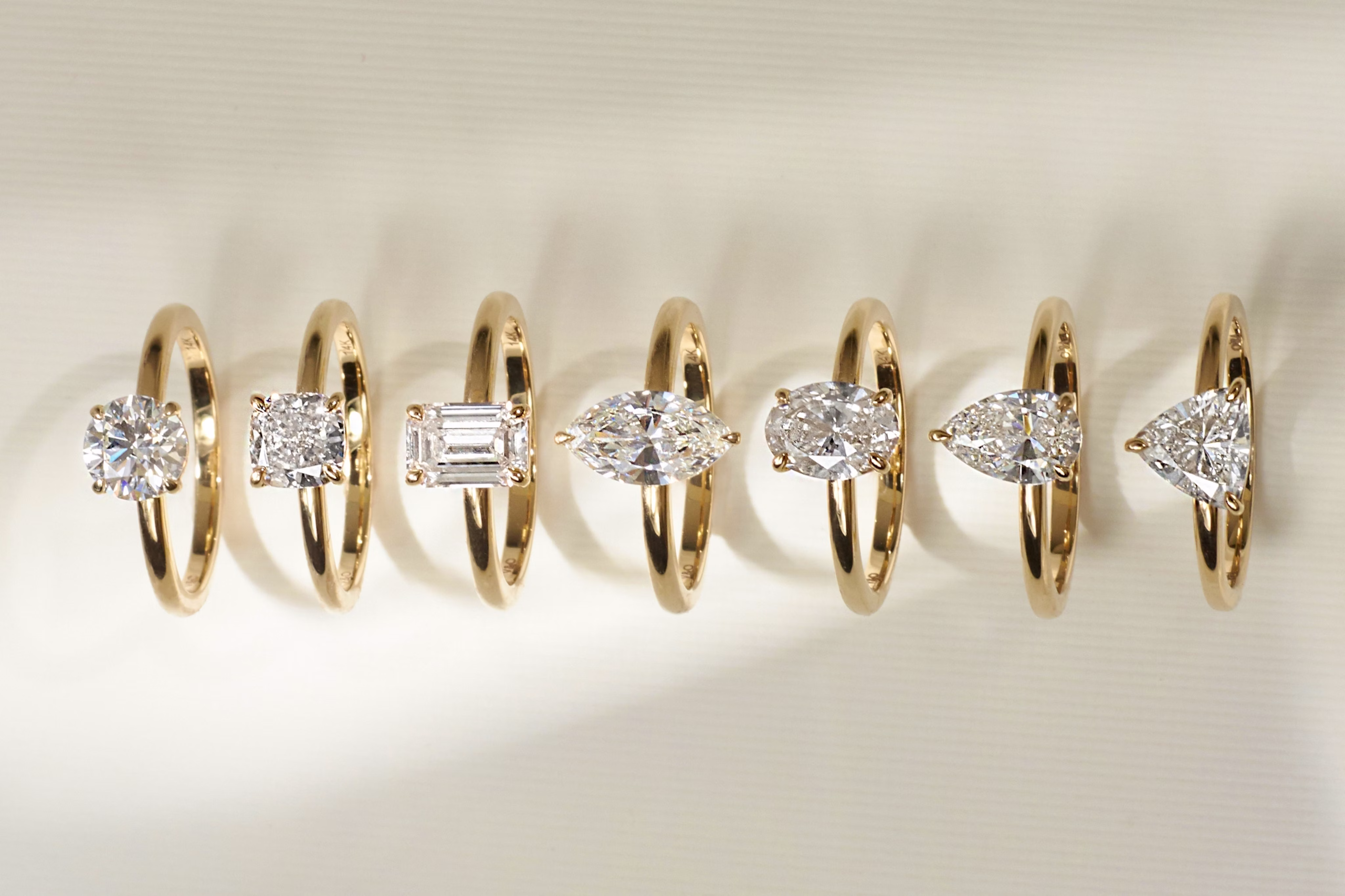 selection of engagement rings with different diamond shapes round brilliant, emerald, princess cut, marquise, pear, trillion