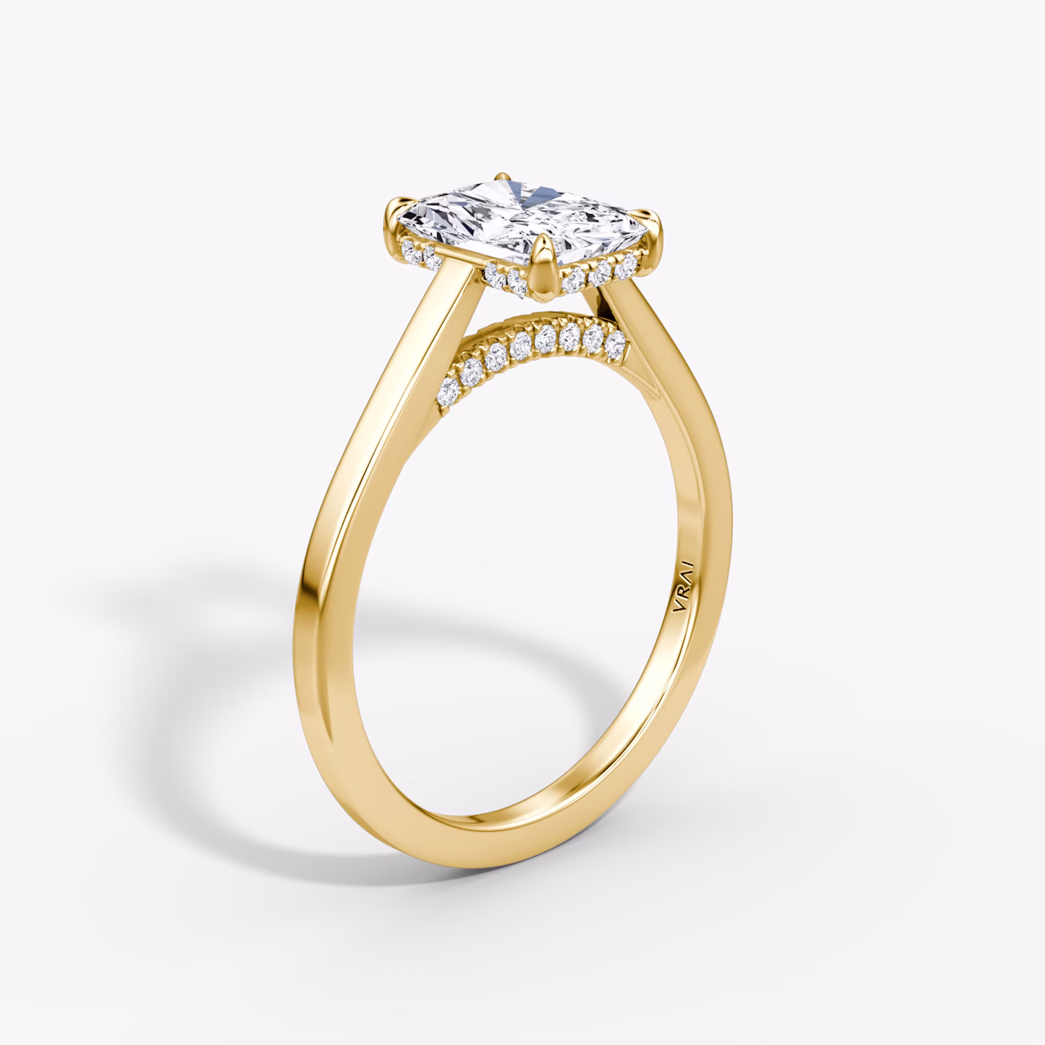 A close-up image of VRAI's Pavé Bridge Radiant Yellow Gold Engagement Ring, standing upright.