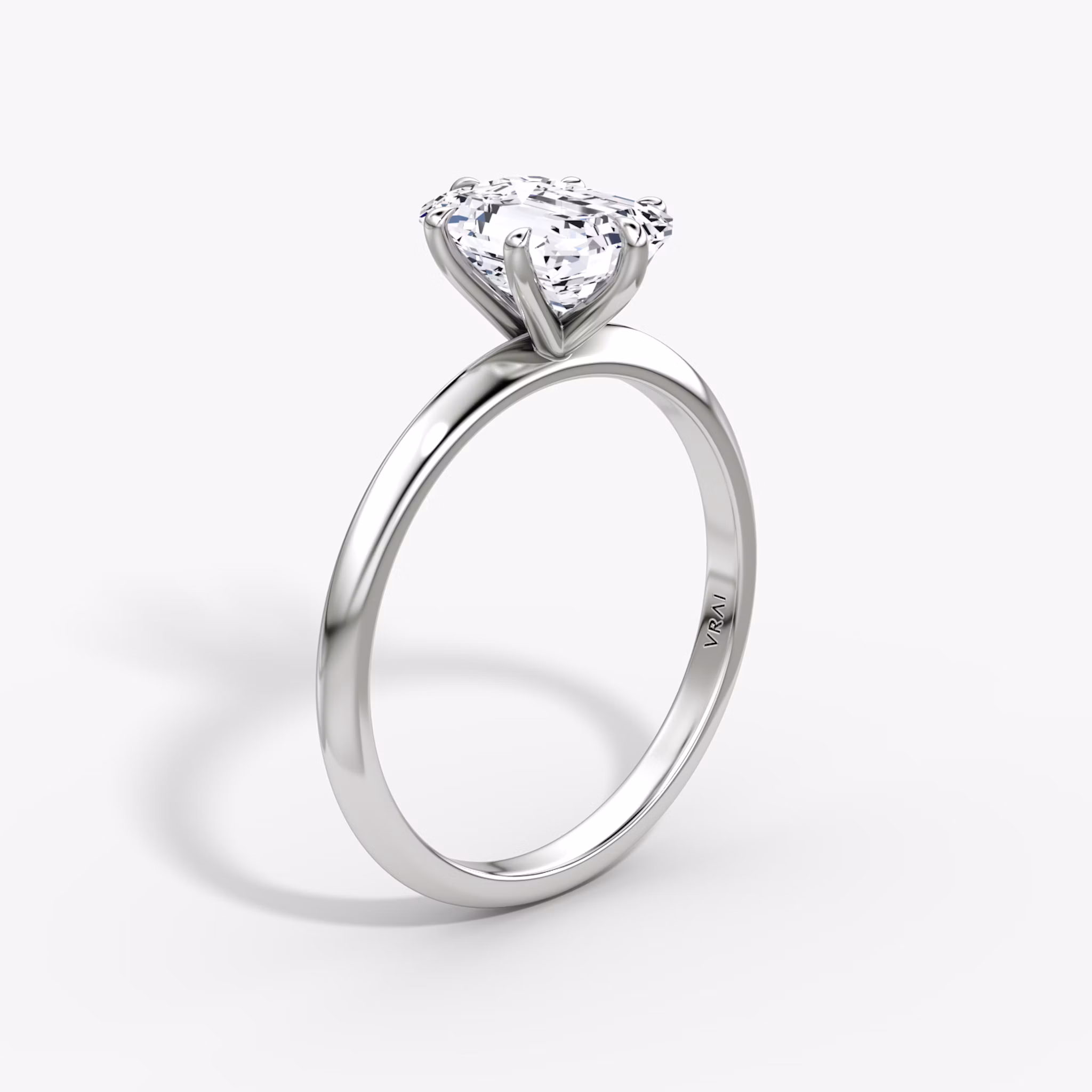 A Knife-Edge Emerald White Gold Engagement Ring standing straight up, against a white background.