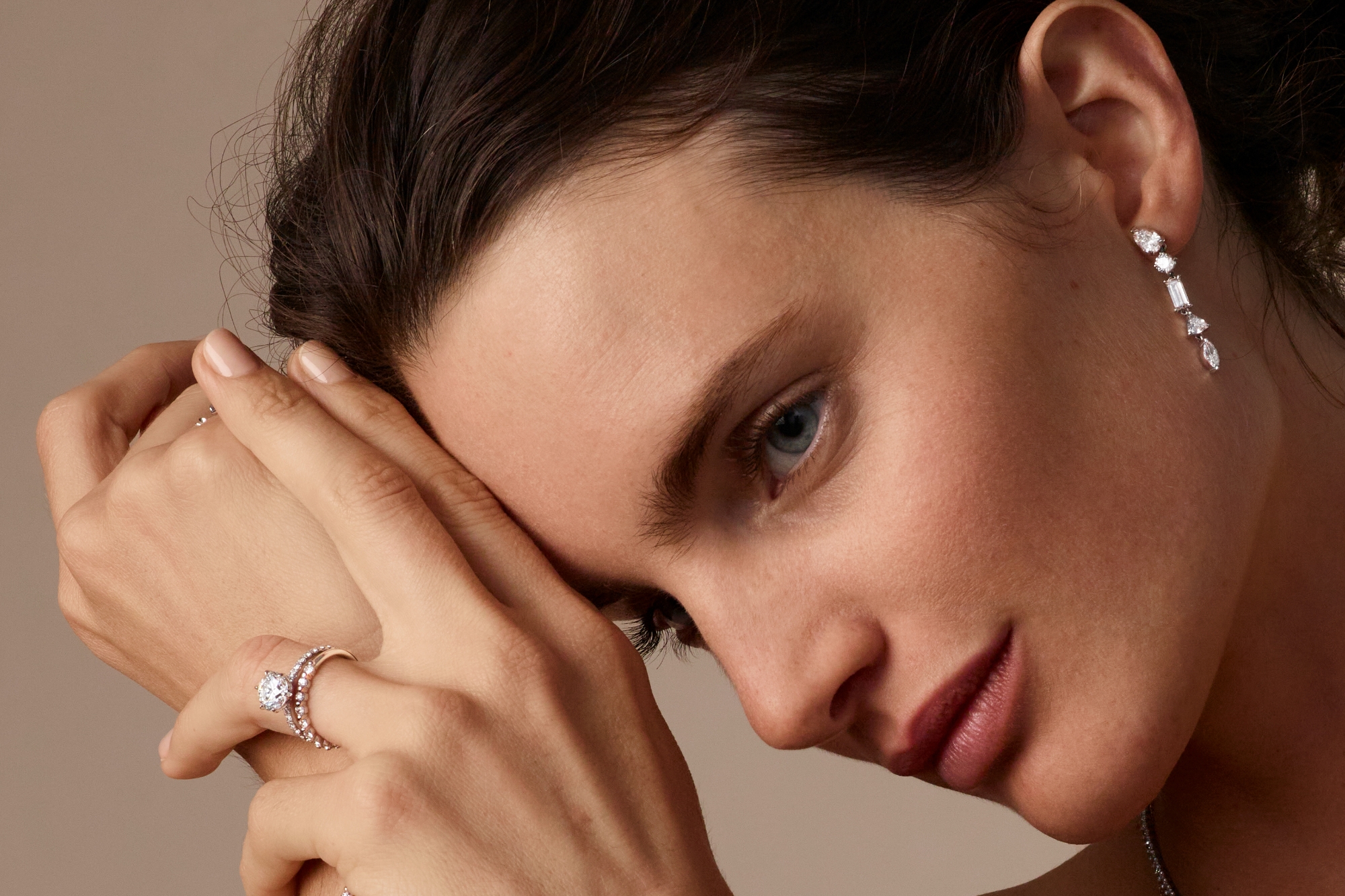 woman wearing an engagement ring and wedding ring with drop earrings