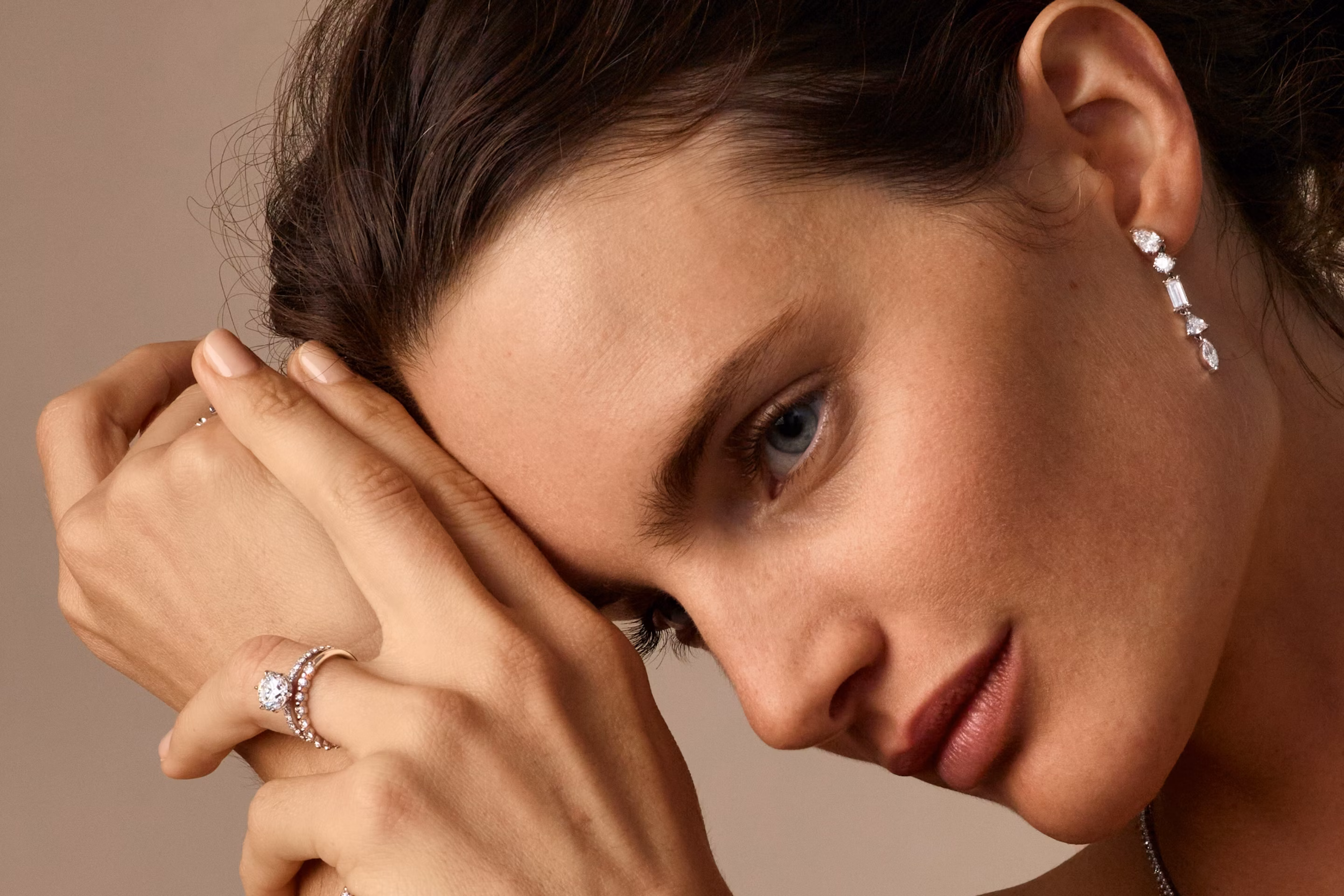 woman wearing an engagement ring and wedding ring with drop earrings