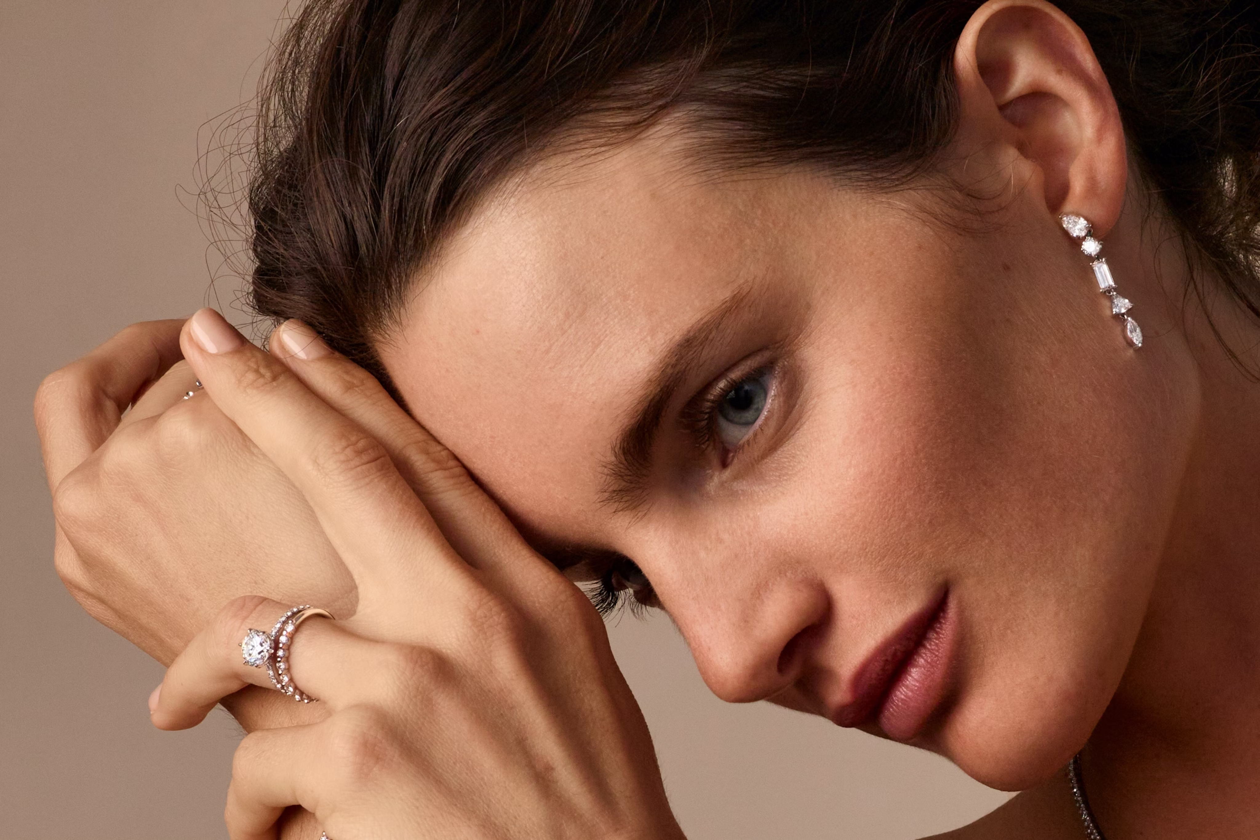 woman wearing an engagement ring and wedding ring with drop earrings