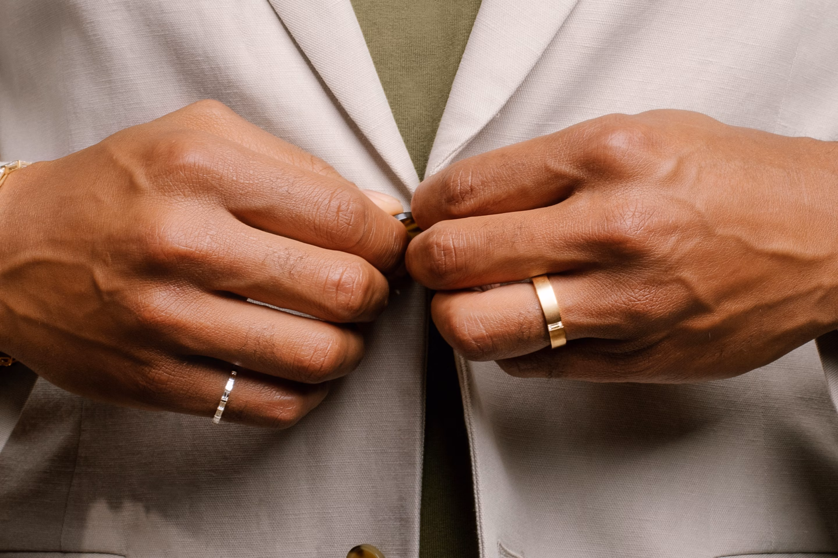 man buttoning up shirt wearing rings on wedding finger and pinky