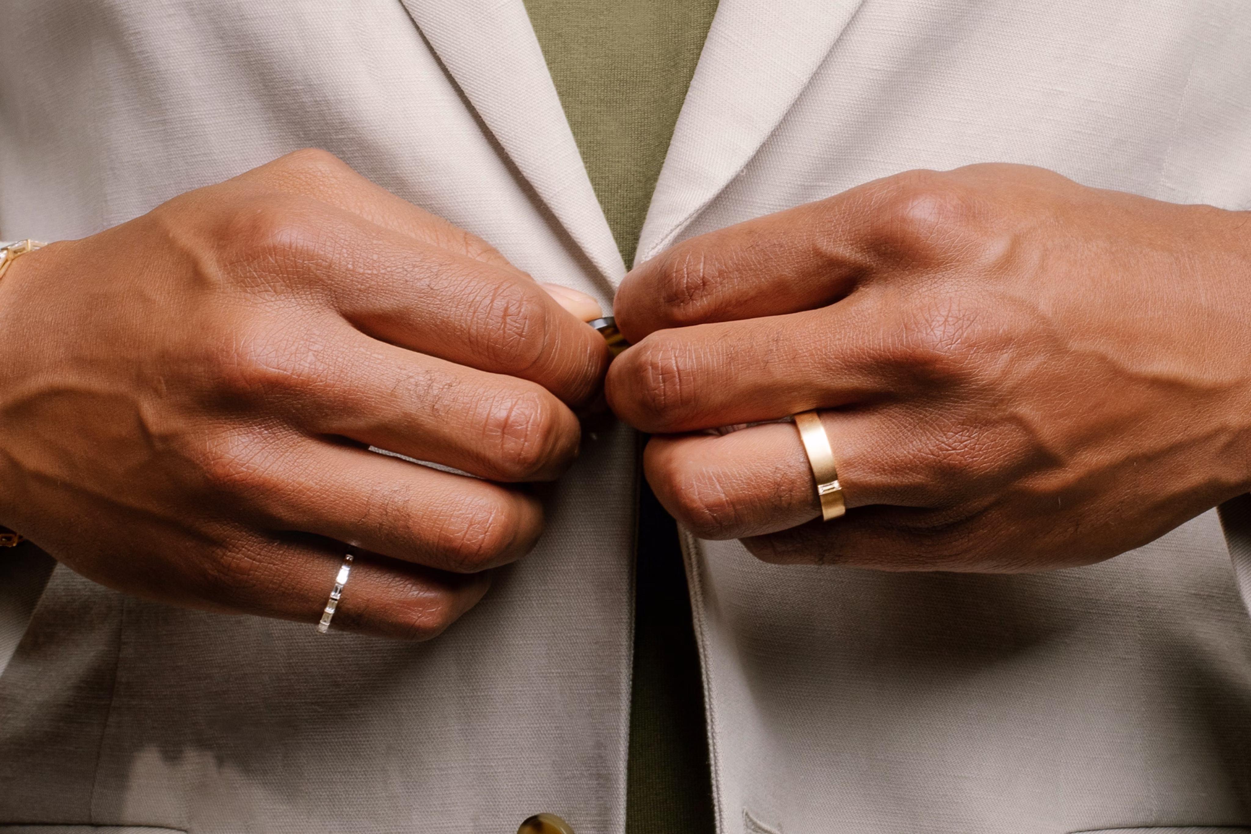 man buttoning up shirt wearing rings on wedding finger and pinky