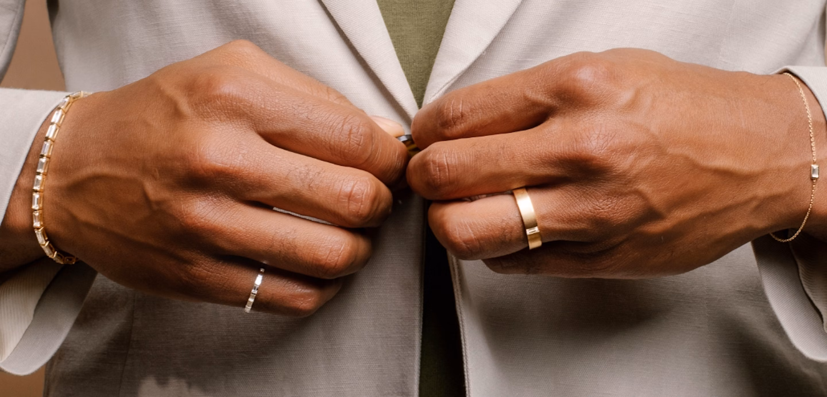 man buttoning up shirt wearing rings on wedding finger and pinky