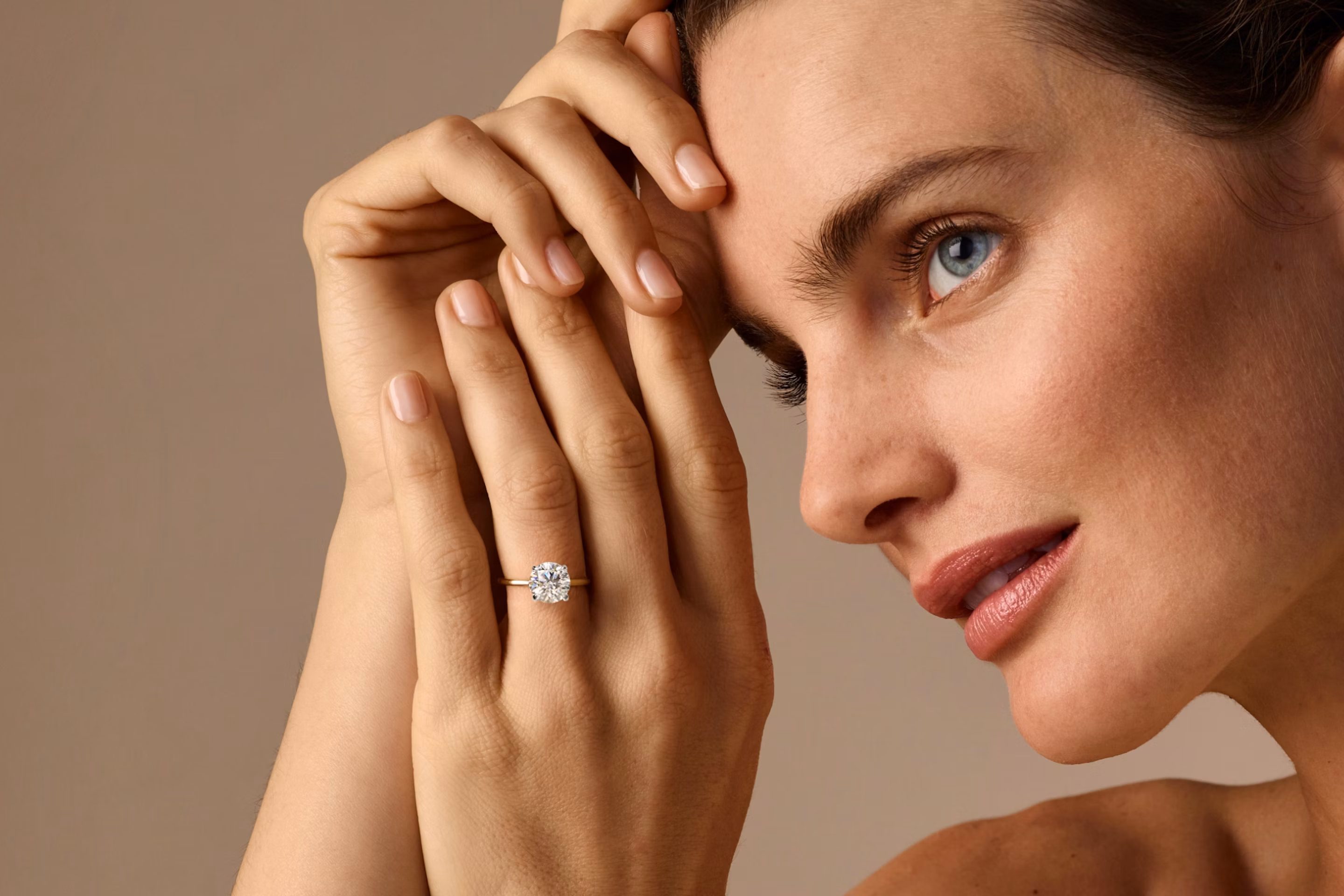 women wearing round brilliant cut engagement ring with both hands and face visible