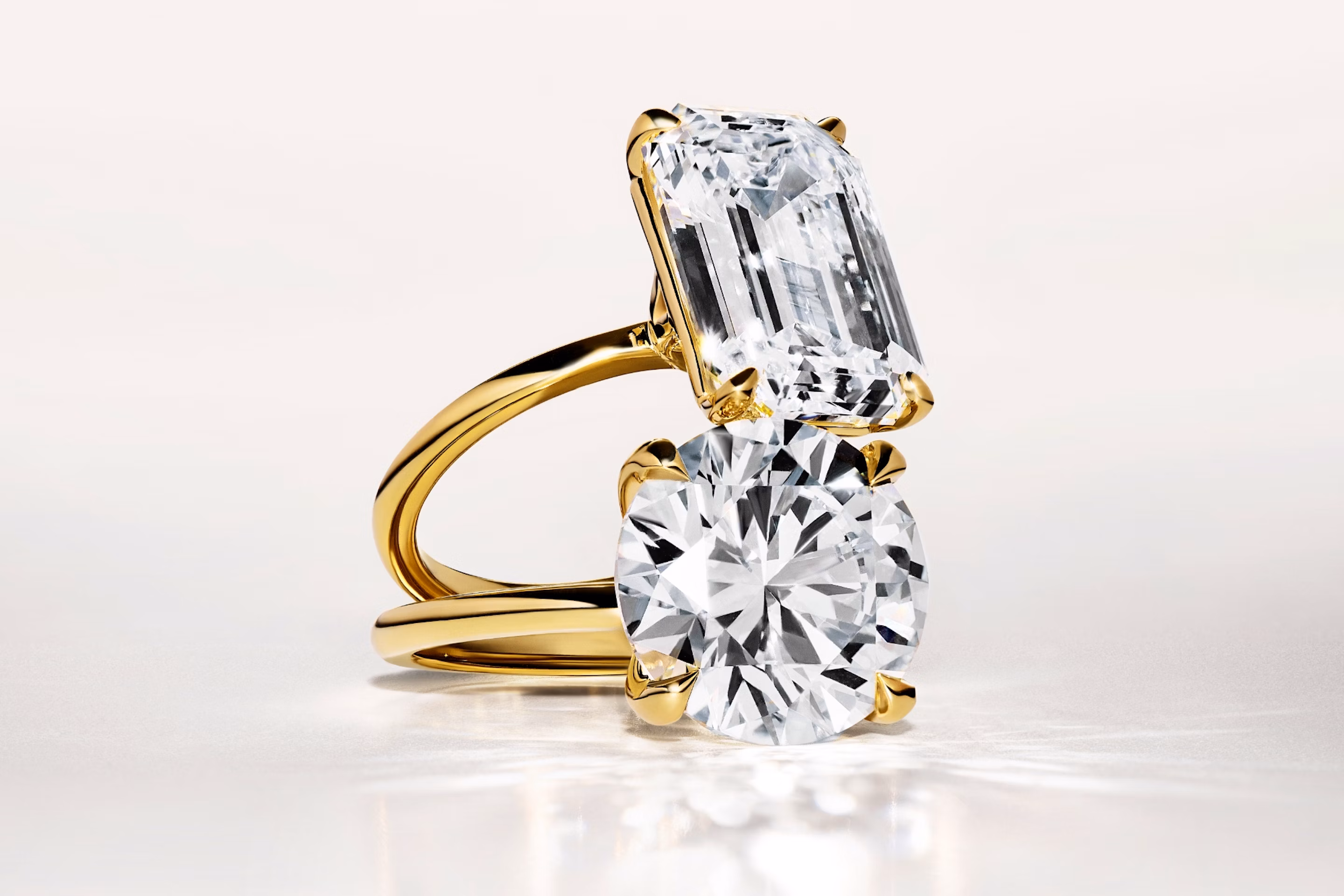 two engagement rings in yellow gold with an emerald cut and a round brilliant cut