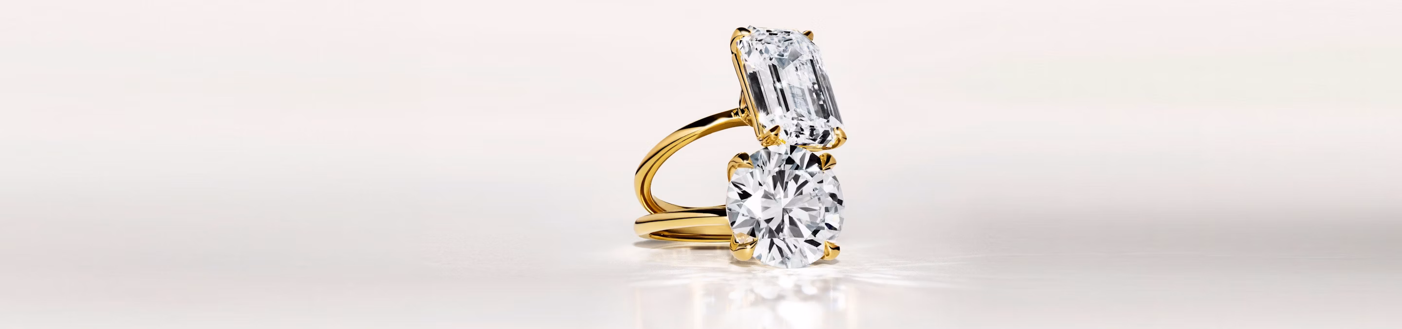 two engagement rings in yellow gold with an emerald cut and a round brilliant cut