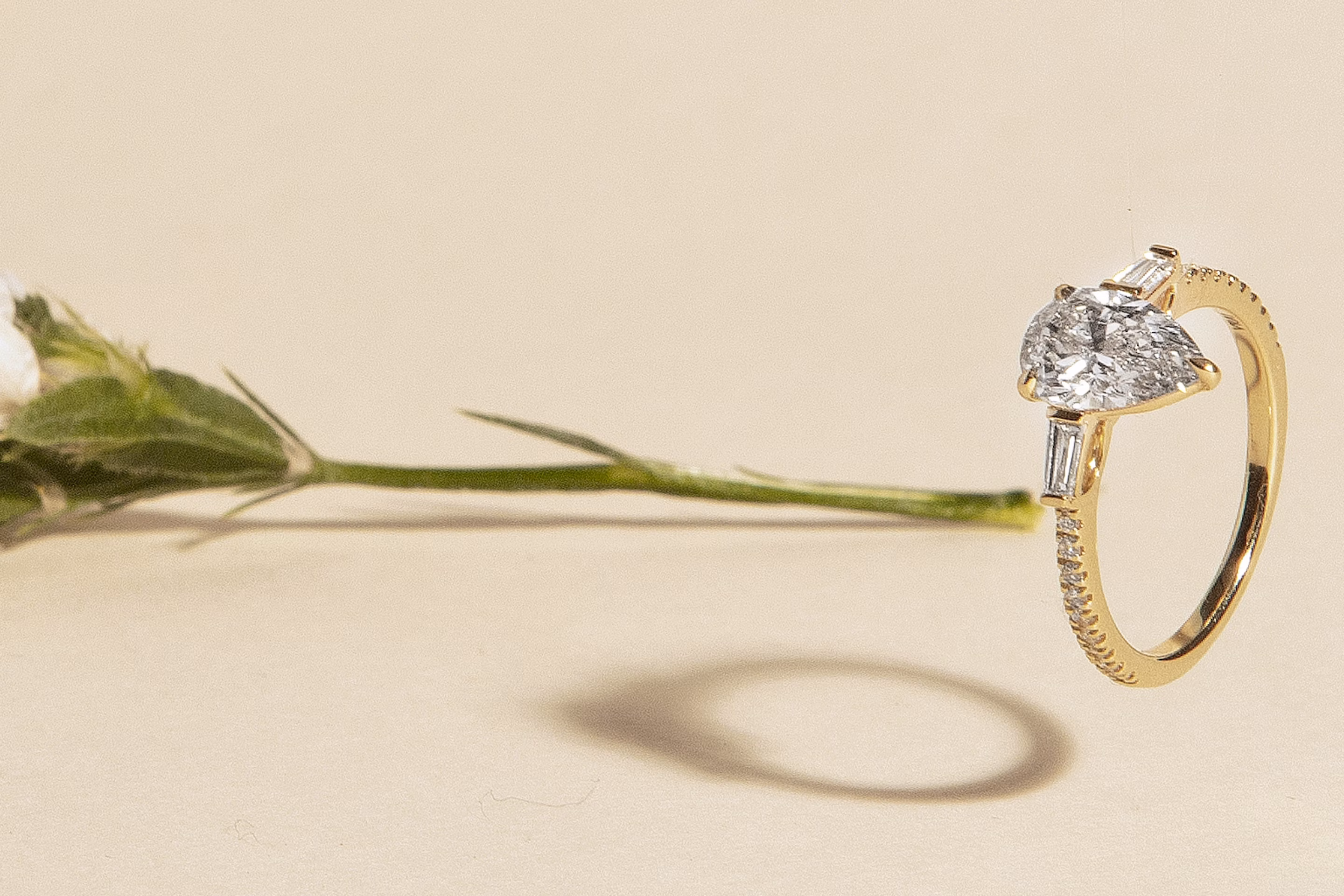 three stone engagement ring with a pear cut lab grown diamond and two baguette side diamonds