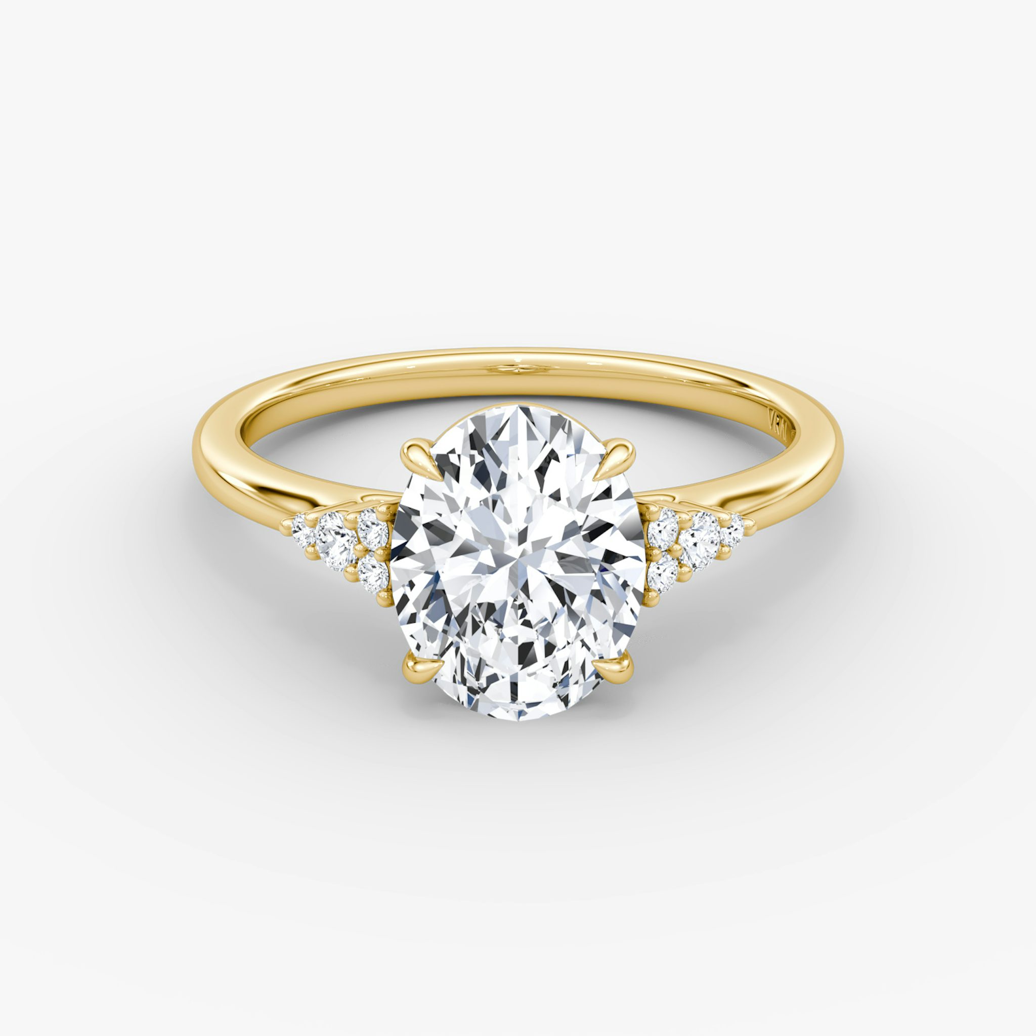 A close-up image of VRAI's Side Cluster Cathedral Oval Yellow Gold Engagement Ring, lying flat.