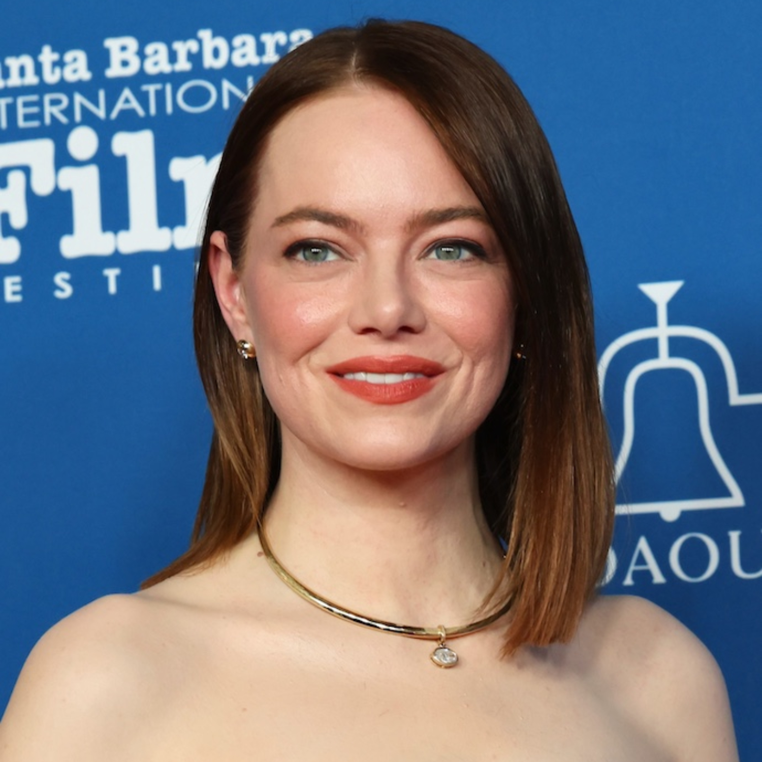A close-up image of Emma Stone wearing a VRAI created gold necklace and earrings.