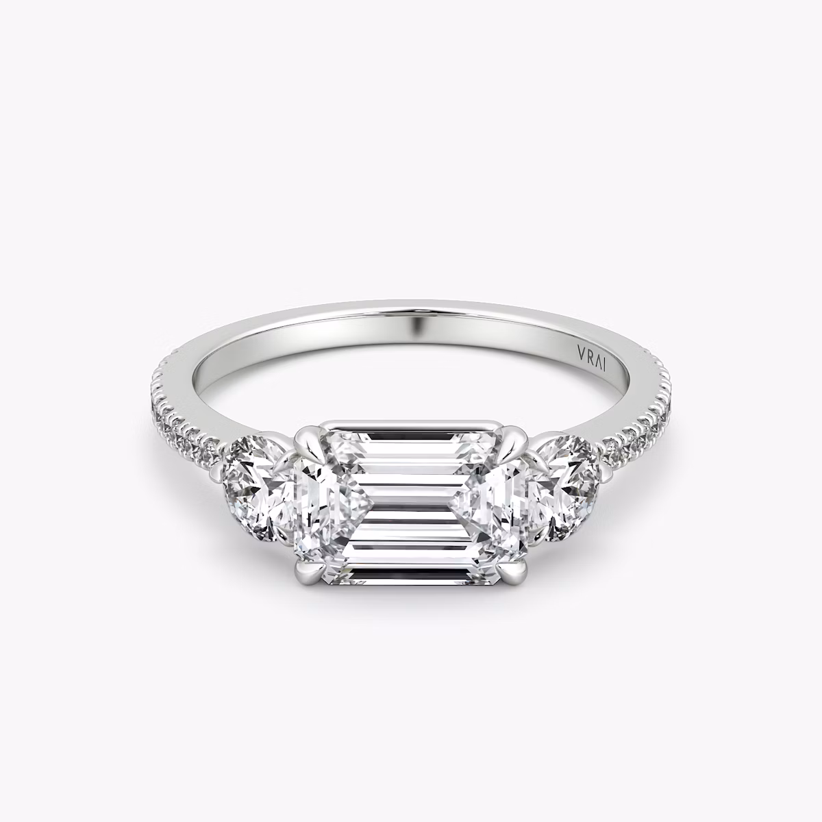 The Three Stone | Emerald | Platinum | bandAccent: Pavé | diamondOrientation: horizontal | sideStoneCarat: 0.25ct | sideStoneShape: Round Brilliant | caratWeight: other