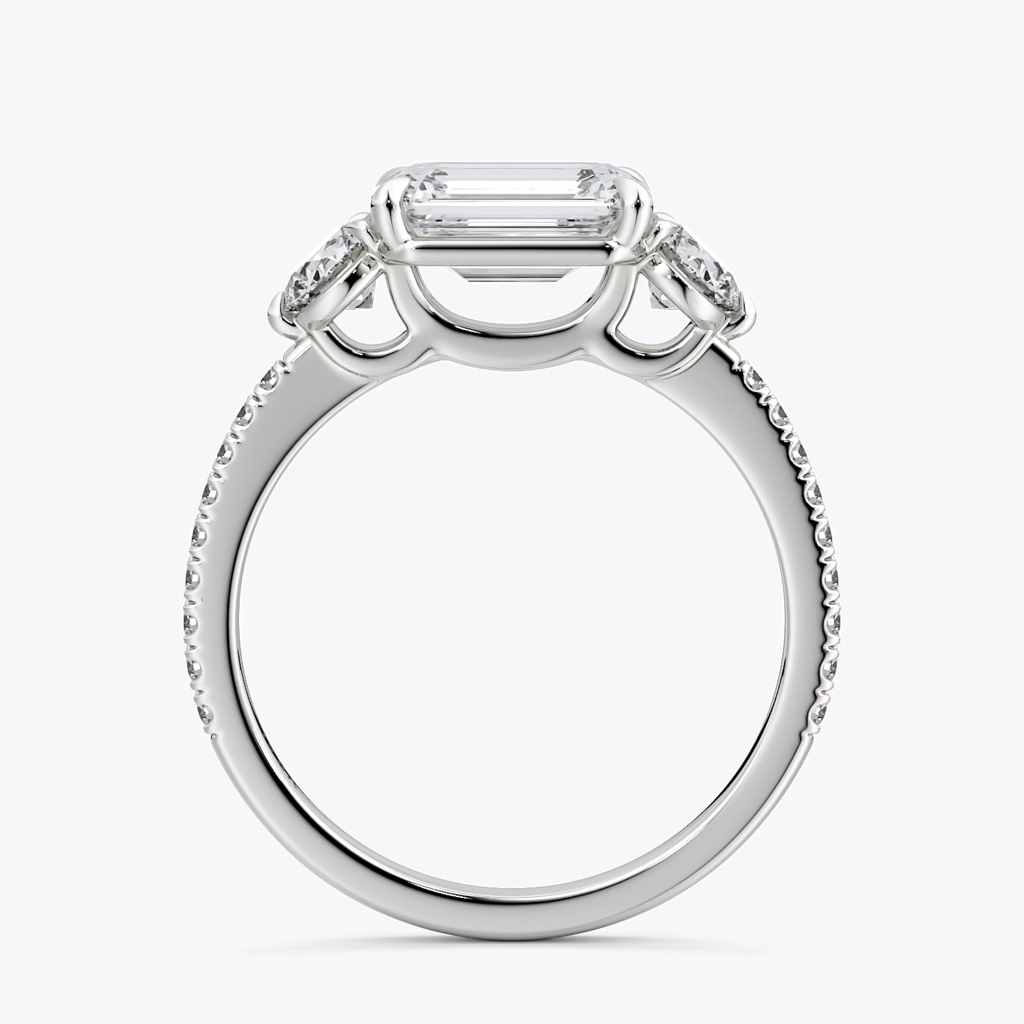 The Three Stone | Emerald | Platinum | bandAccent: Pavé | diamondOrientation: horizontal | sideStoneCarat: 0.25ct | sideStoneShape: Round Brilliant | caratWeight: other