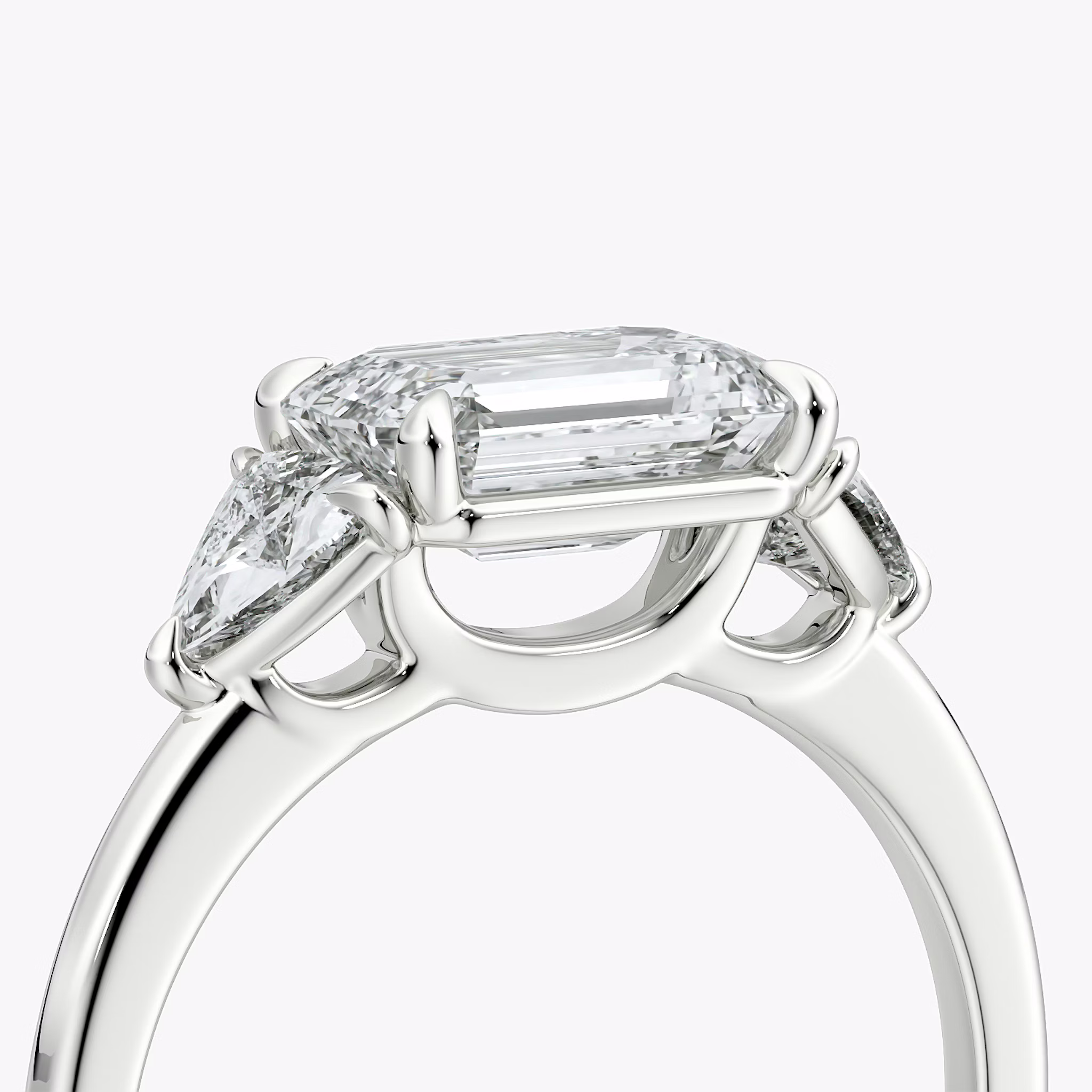 The Three Stone | Emerald | 18k | White Gold | bandAccent: Plain | diamondOrientation: horizontal | sideStoneCarat: 0.25ct | sideStoneShape: Trillion | caratWeight: other