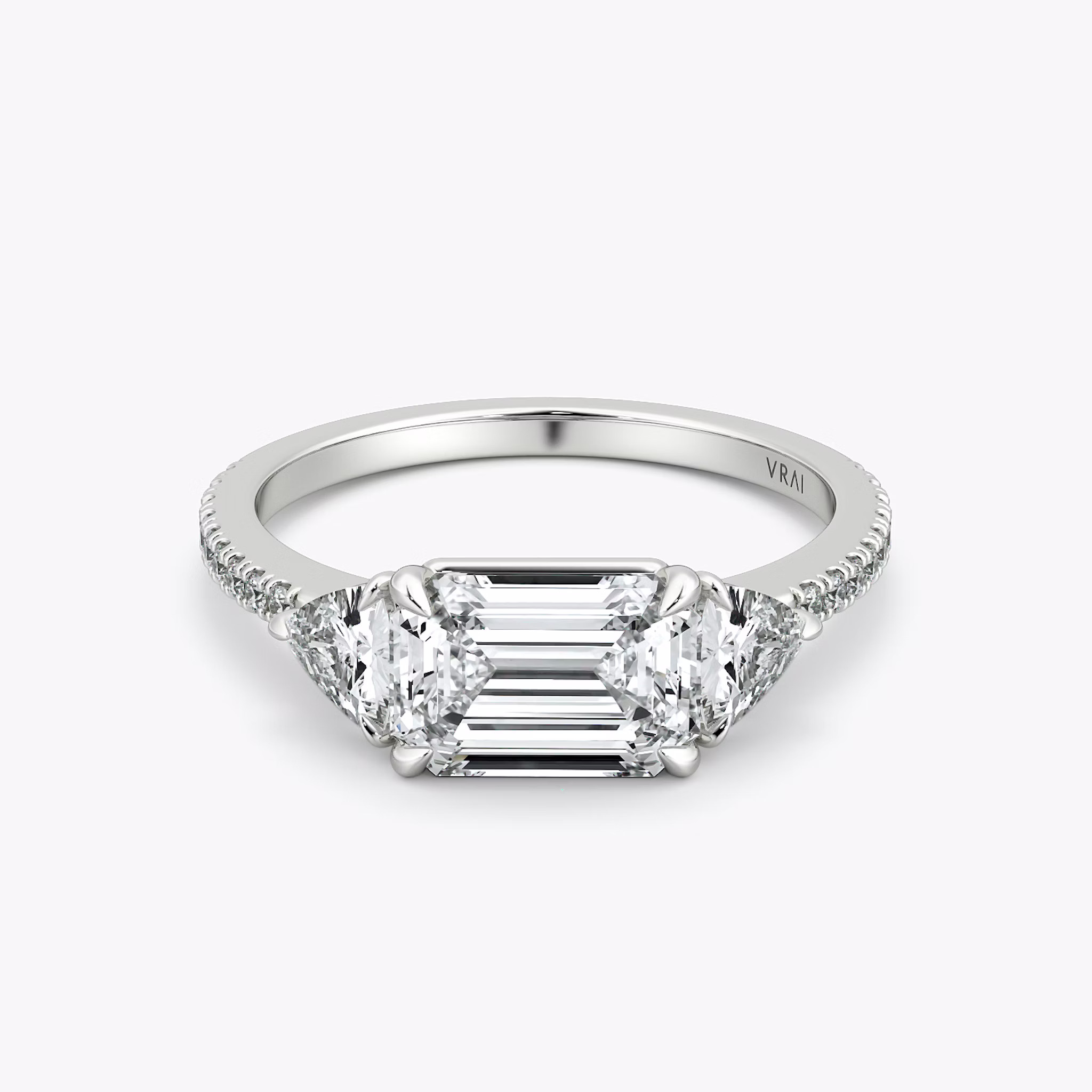 The Three Stone | Emerald | Platinum | bandAccent: Pavé | diamondOrientation: horizontal | sideStoneCarat: 0.25ct | sideStoneShape: Trillion | caratWeight: other