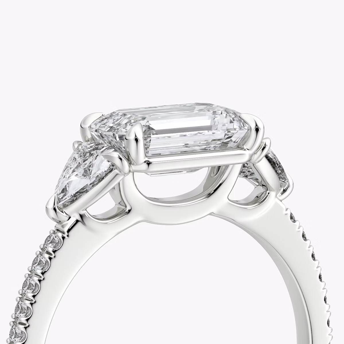 The Three Stone | Emerald | Platinum | bandAccent: Pavé | diamondOrientation: horizontal | sideStoneCarat: 0.25ct | sideStoneShape: Trillion | caratWeight: other