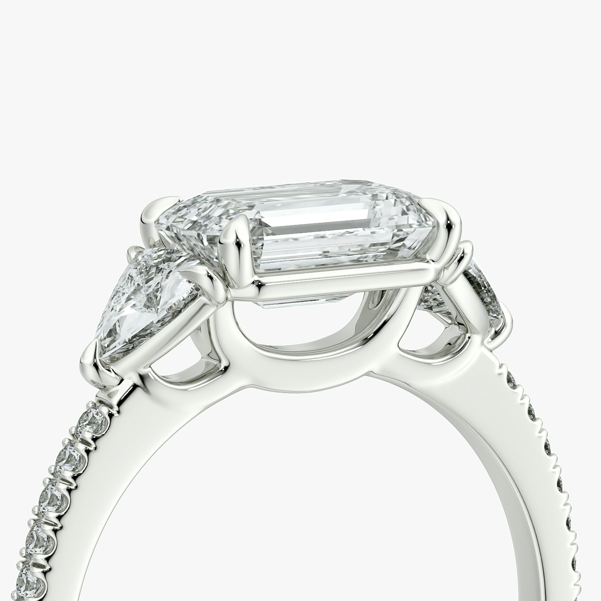 The Three Stone | Emerald | Platinum | bandAccent: Pavé | diamondOrientation: horizontal | sideStoneCarat: 0.25ct | sideStoneShape: Trillion | caratWeight: other
