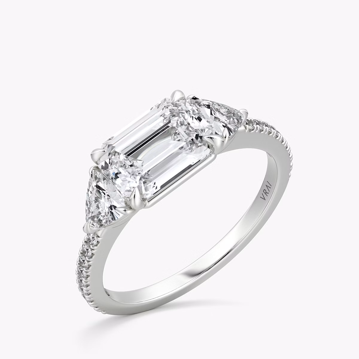 The Three Stone | Emerald | Platinum | bandAccent: Pavé | diamondOrientation: horizontal | sideStoneCarat: 0.25ct | sideStoneShape: Trillion | caratWeight: other
