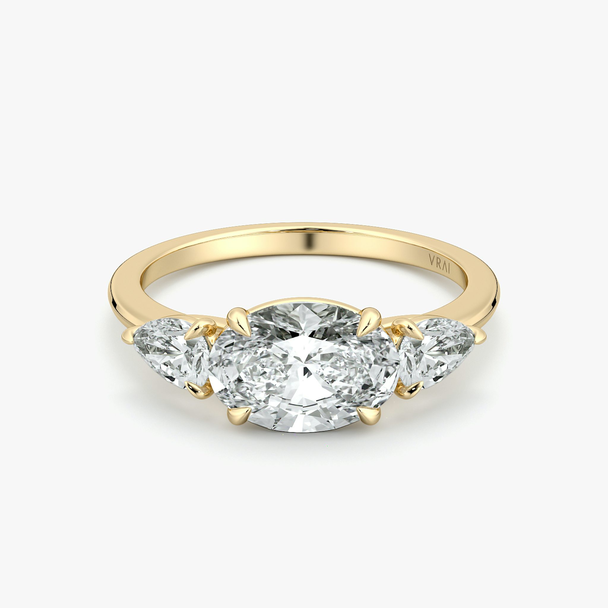 Oval-east-west-three-stone engagement ring with pear side stones on yellow gold band, front view on white background.