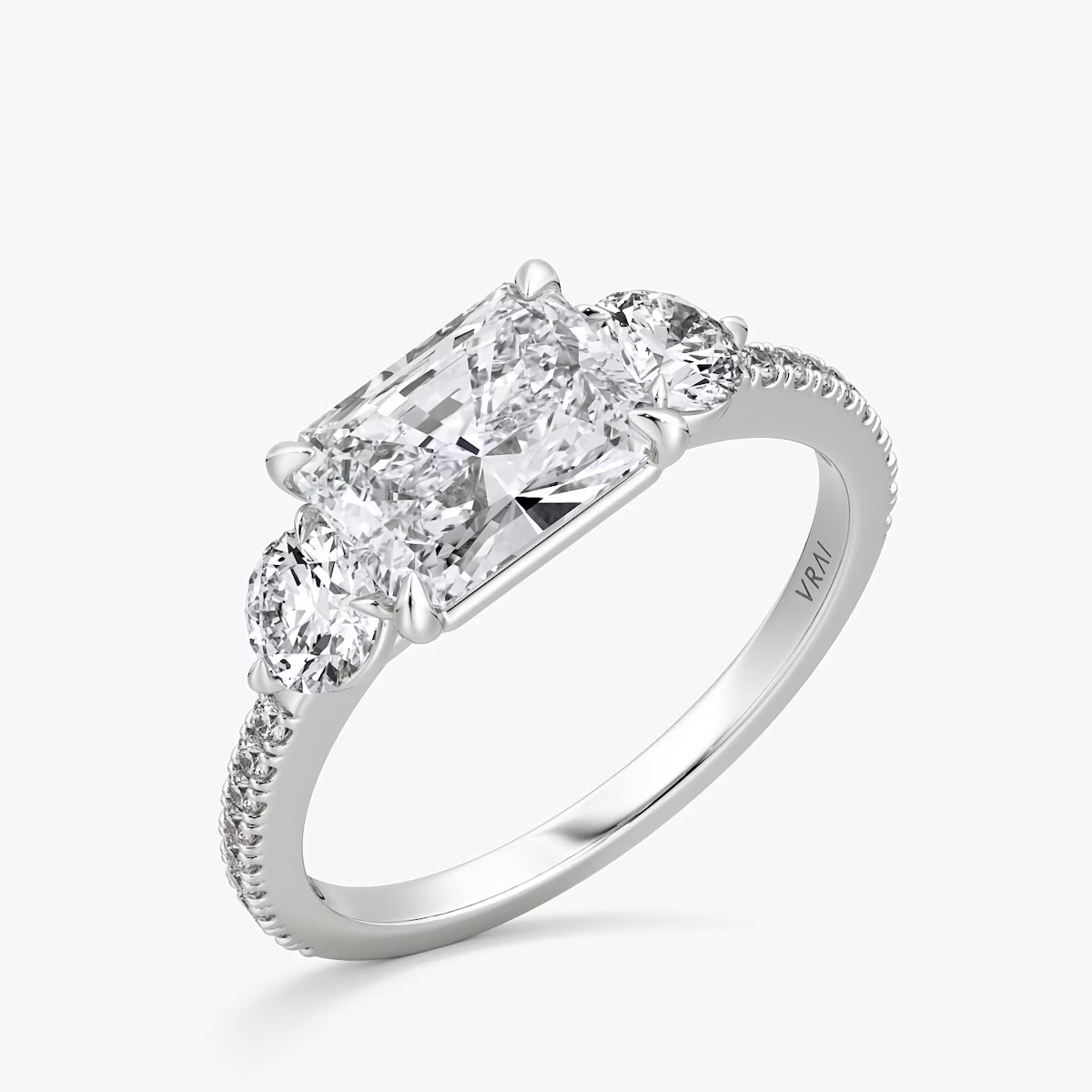 The Three Stone | Radiant | 18k | White Gold | bandAccent: Pavé | diamondOrientation: horizontal | sideStoneCarat: 0.25ct | sideStoneShape: Round Brilliant | caratWeight: other