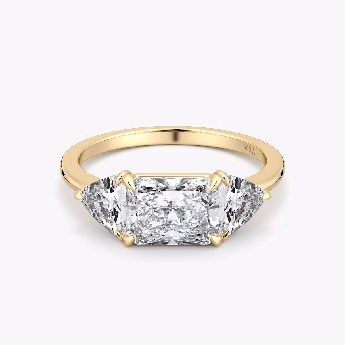 Radiant-cut and trillion-cut three-stone ring with plain yellow gold band, East-West 0.50ct setting.