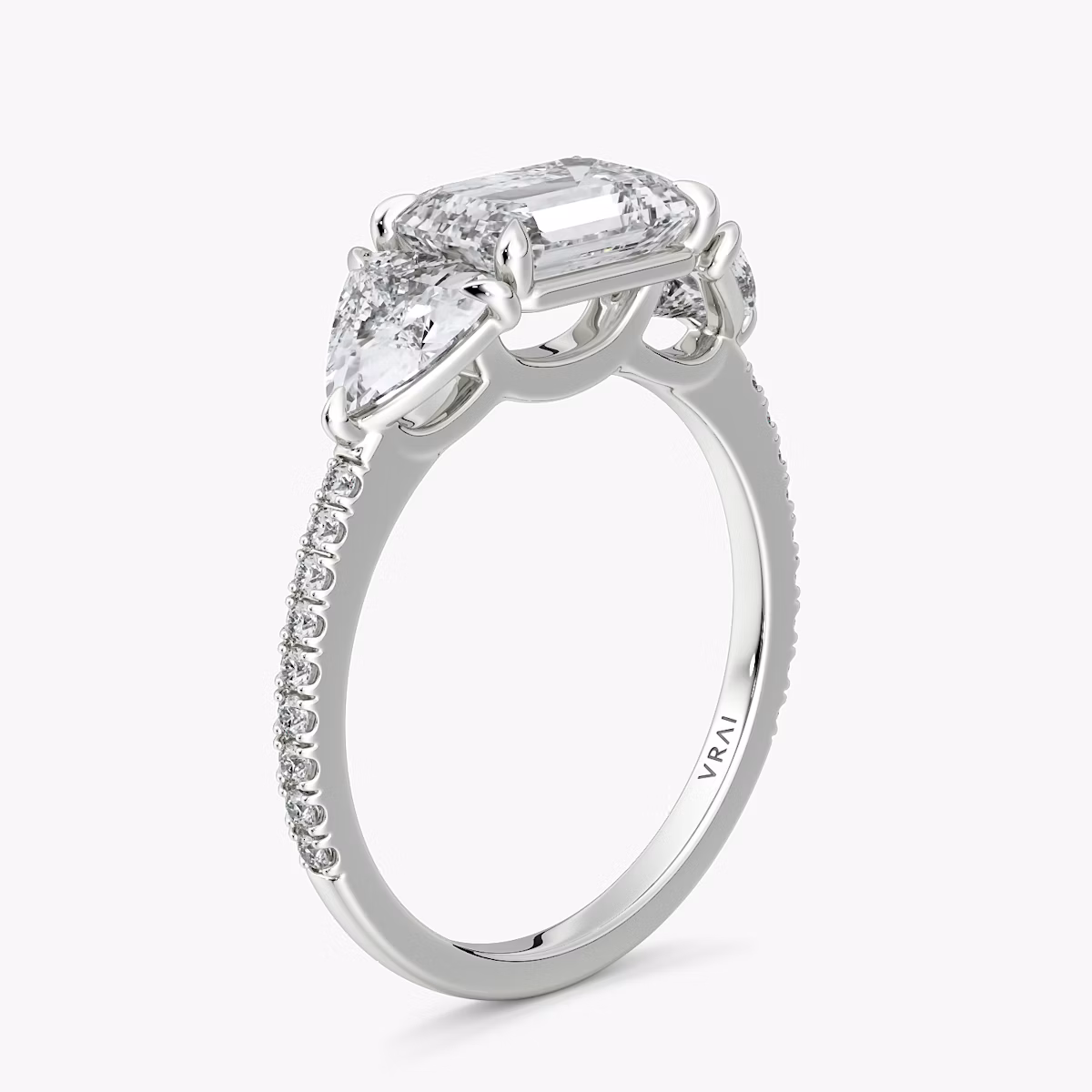 The Three Stone | Emerald | Platinum | bandAccent: Pavé | diamondOrientation: horizontal | sideStoneCarat: 0.50ct | sideStoneShape: Trillion | caratWeight: other