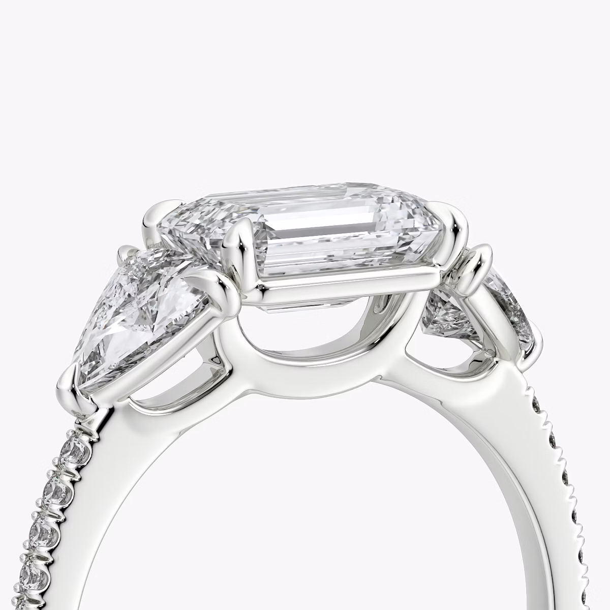 The Three Stone | Emerald | Platinum | bandAccent: Pavé | diamondOrientation: horizontal | sideStoneCarat: 0.50ct | sideStoneShape: Trillion | caratWeight: other