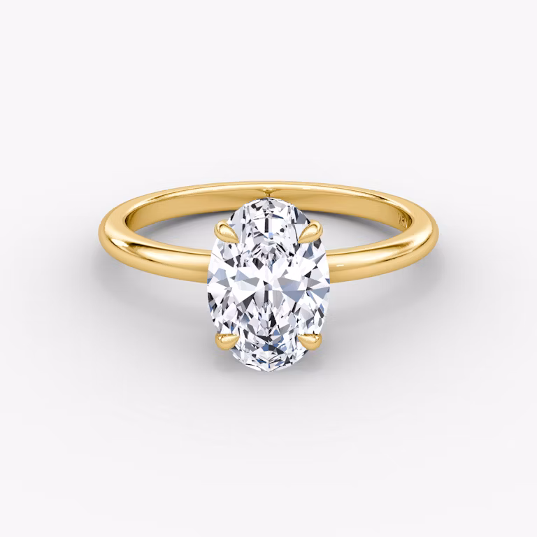 A close-up image of VRAI's Signature Oval Yellow Gold Engagement Ring, lying flat.