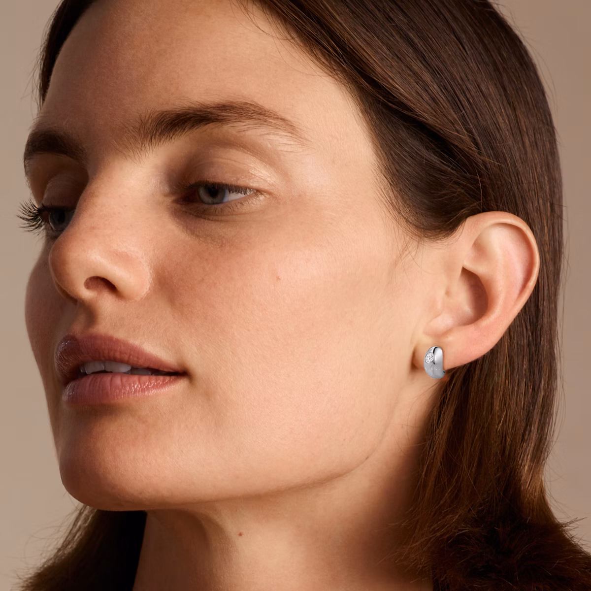Model wearing white gold dome huggie hoop
