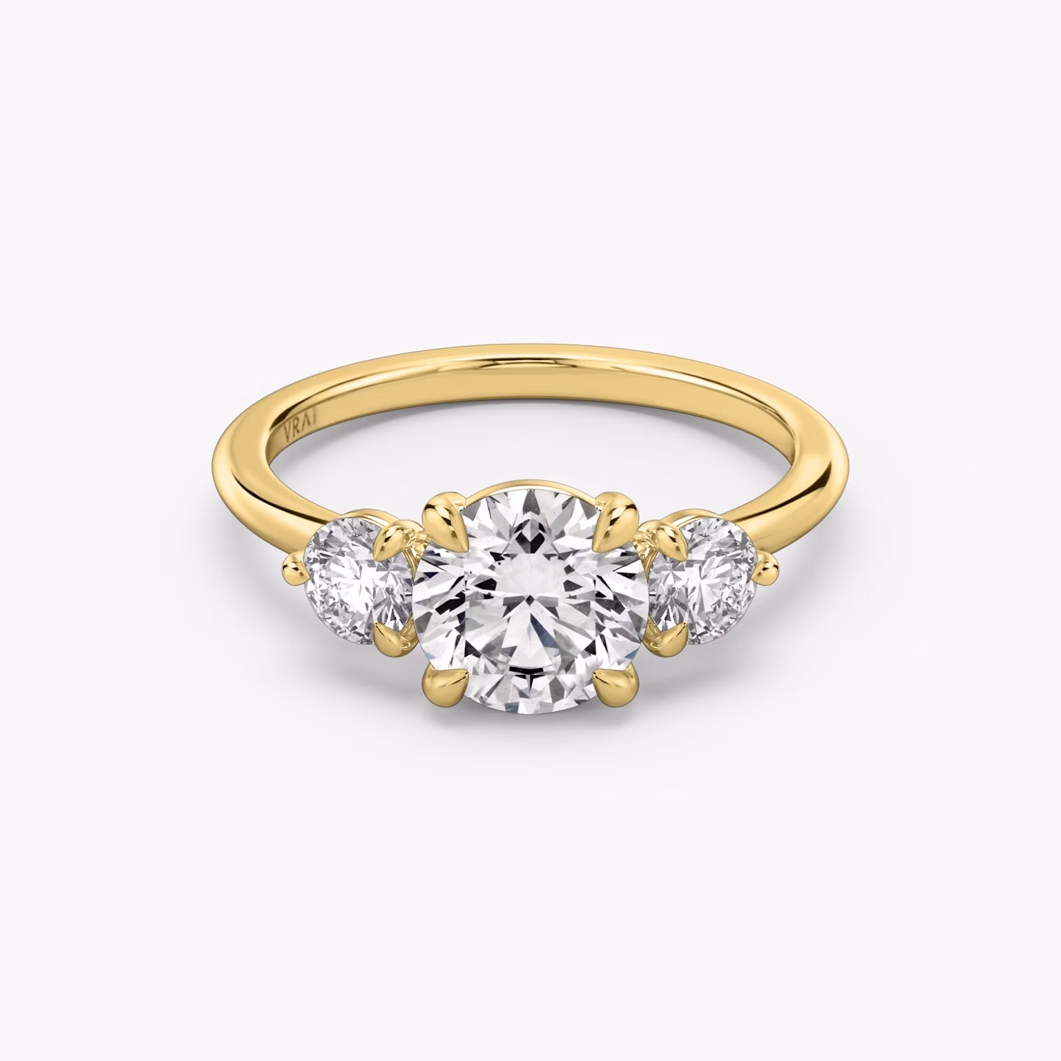 Three-stone engagement ring featuring a round center diamond with two matching side stones on a sleek metal band.