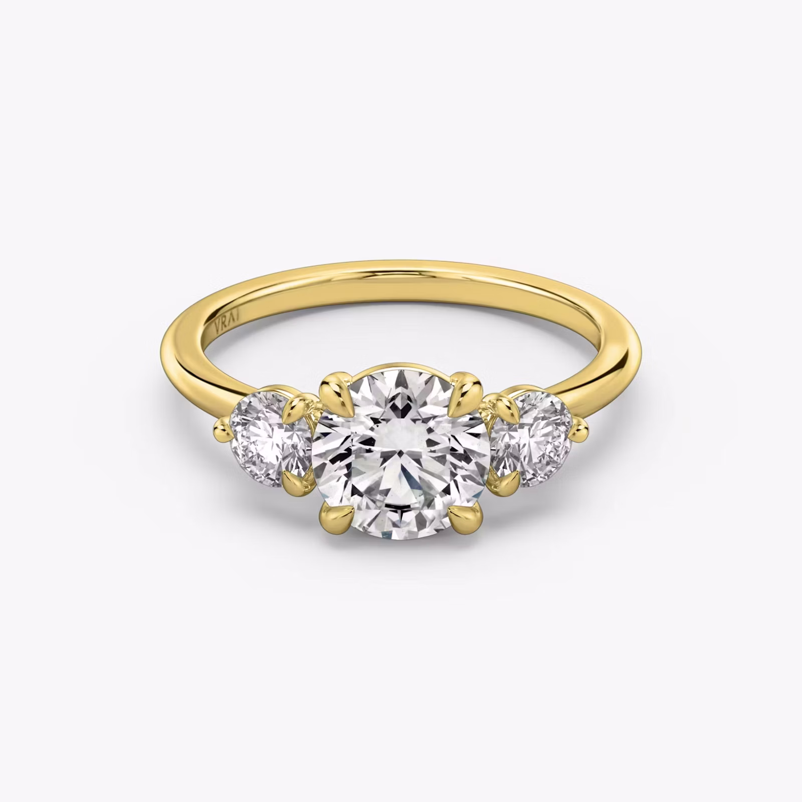 Three-stone engagement ring featuring a round center diamond with two matching side stones on a sleek metal band.