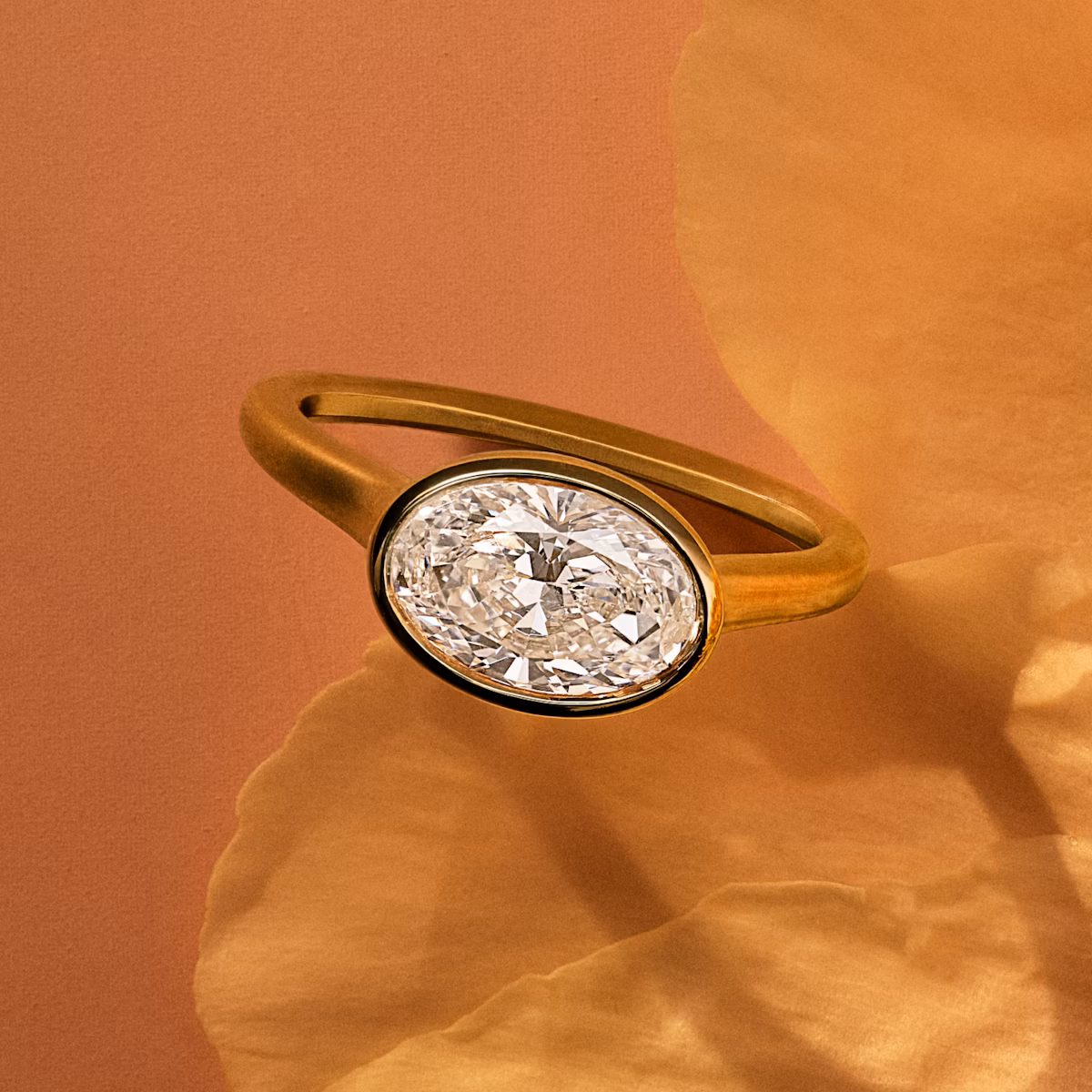 Yellow gold bezel set oval engagement ring on a flower petal