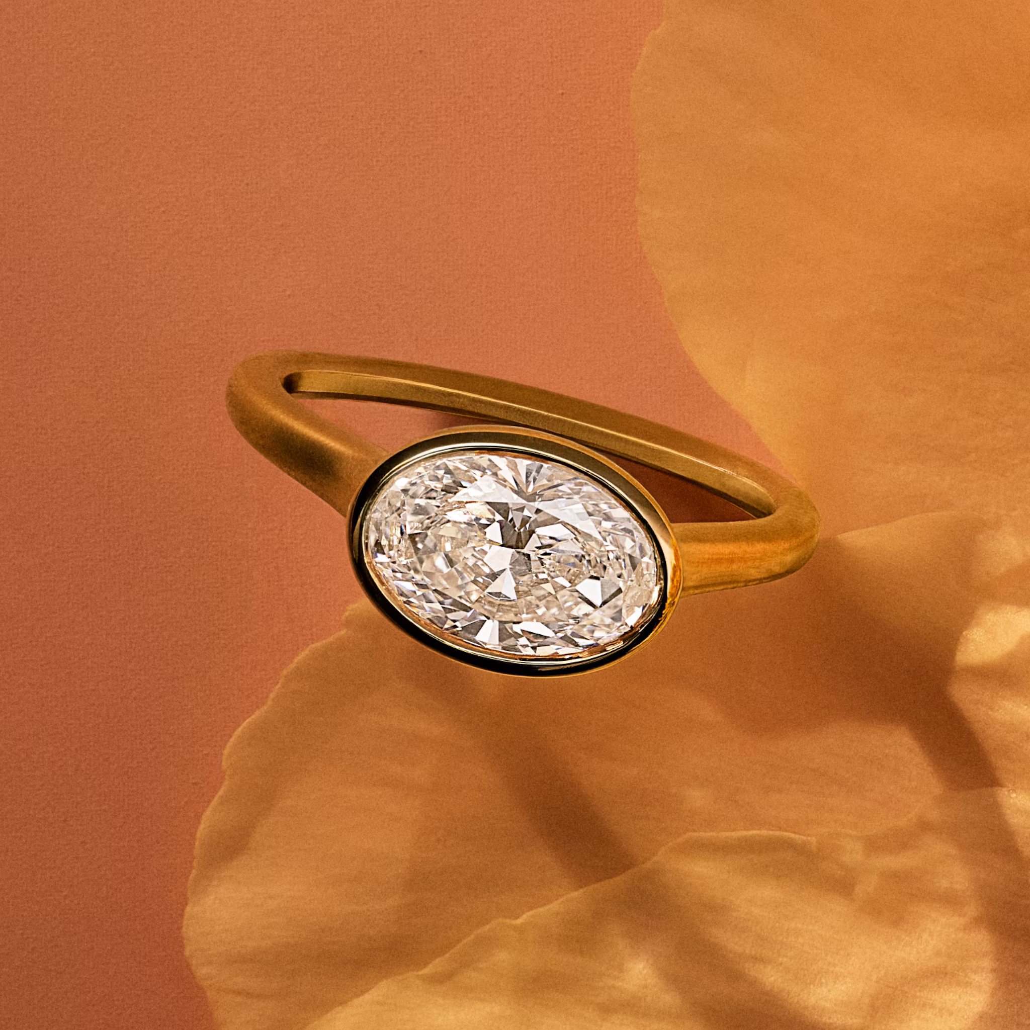 Yellow gold bezel set oval engagement ring on a flower petal