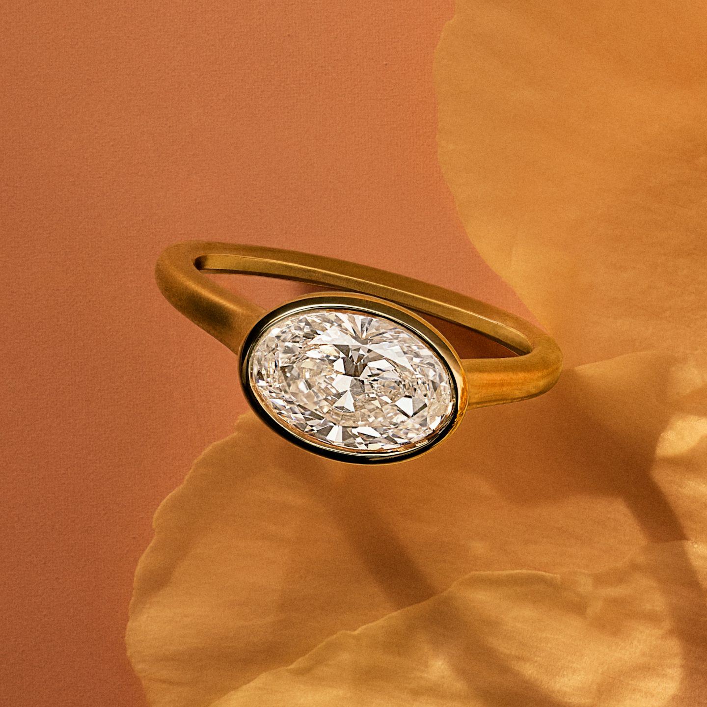 Yellow gold bezel set oval engagement ring on a flower petal
