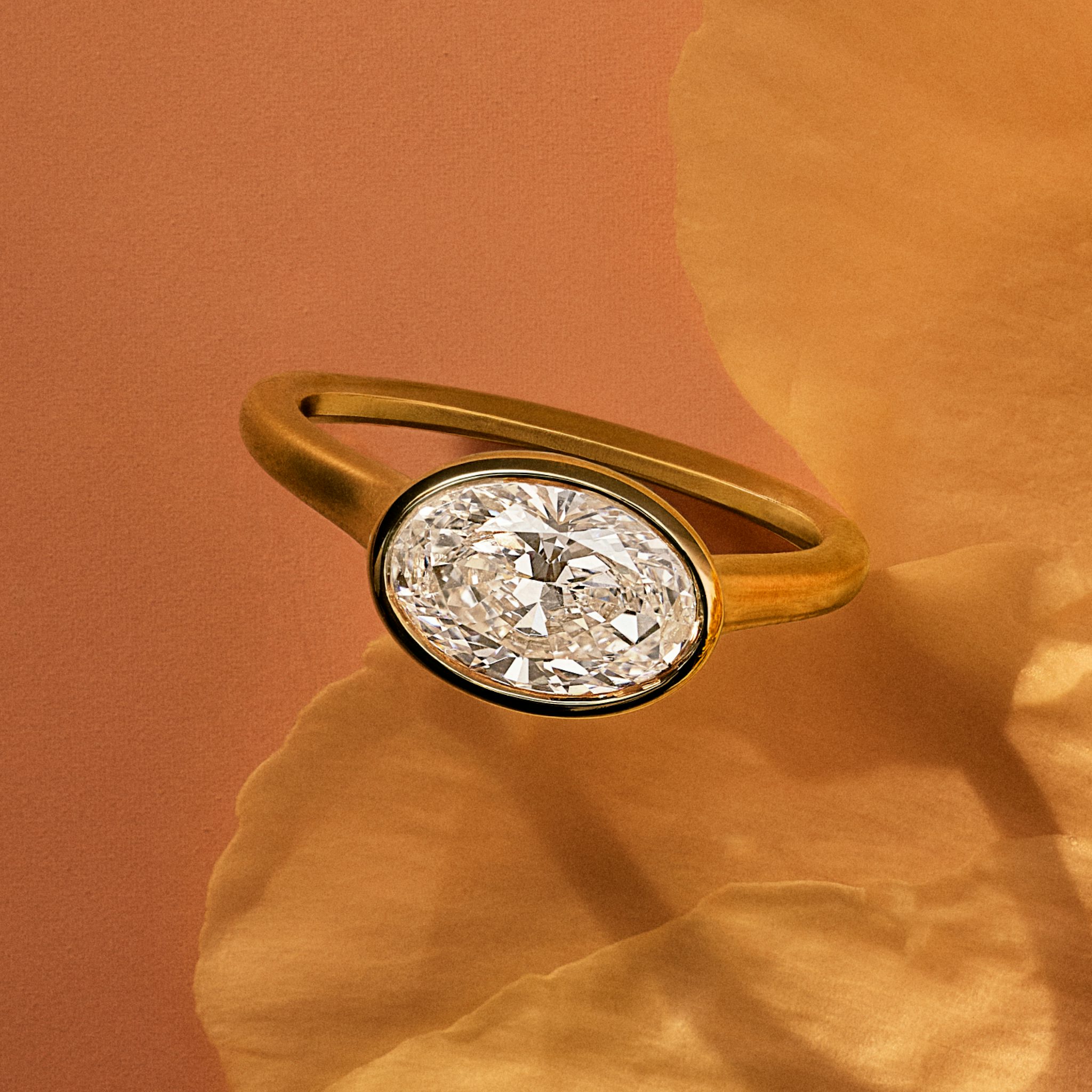 Yellow gold bezel set oval engagement ring on a flower petal