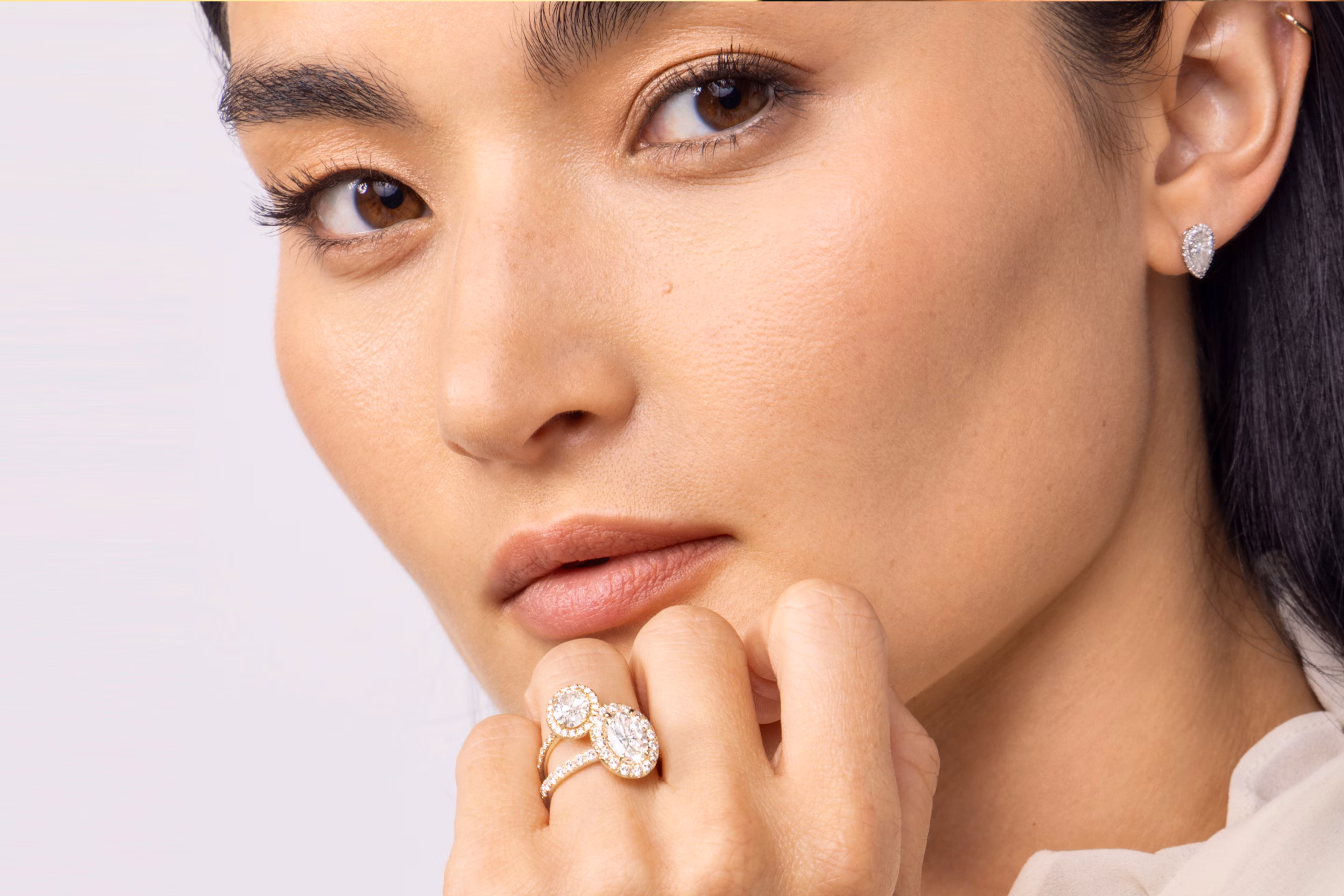 Model wearing two halo engagement rings