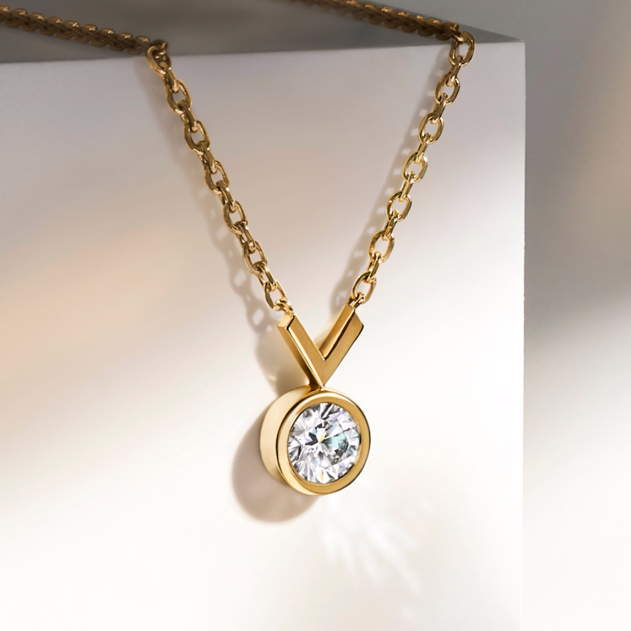 Yellow gold necklace with lab grown round cut diamond hanging from table