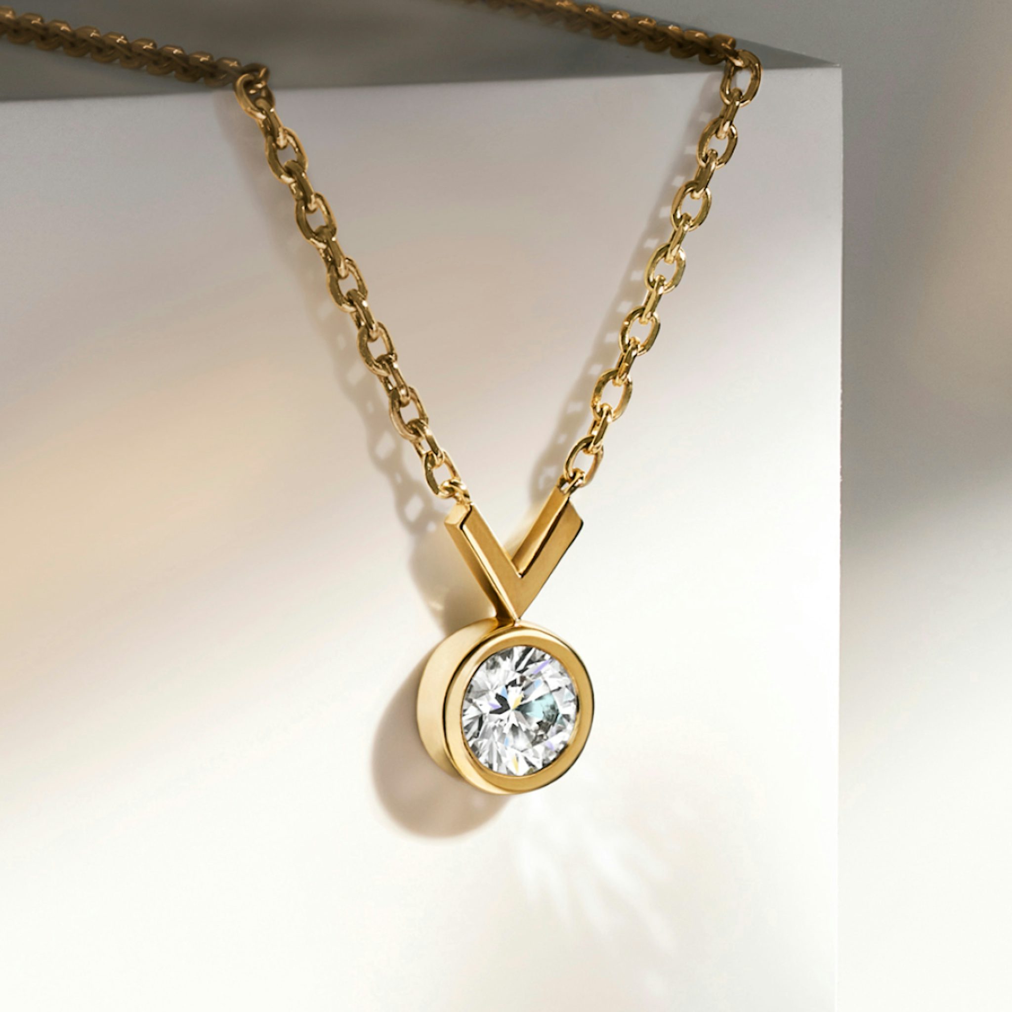 Yellow gold necklace with lab grown round cut diamond hanging from table